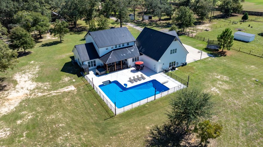 Modern farmhouse dreams meet next-level homestead living at 13796 State Hwy 81 in Ponce de Leon. Set behind full perimeter fencing on 20 pristine acres, this newly built estate delivers the rare balance of designer finishes, functional spaces, and true self-sufficient country living without sacrificing style. Inside the 5-bedroom, 4 full-bath, 2 half-bath farmhouse, clean lines and thoughtful details shine. The chef's kitchen anchors the home with white shaker cabinetry, under-cabinet lighting, custom vent hood, pot filler, butcher block countertops, and an oversized island that flows seamlessly into the open living space. A walk-in pantry with custom cabinetry and a dedicated coffee bar with beverage fridge elevates everyday living. The primary suite, tucked privately on the main level, feels like a retreat featuring a vaulted, beamed ceiling, abundant natural light, and a spa-inspired bath with freestanding soaking tub, glass-tiled rainfall shower, and a custom walk-in closet. Upstairs, two bedrooms offer ensuite baths and custom closets, while a bonus loft/bedroom above the 3-car garage includes its own AC, full bath, storage, and flexible space ideal for guests, a home office, or creative studio. Step outside and the lifestyle continues. The 3-car garage opens directly to a private resort-style patio complete with a 7.5-ft saltwater pool, hot tub, sauna, and cold plunge perfect for entertaining or unwinding at the end of the day. For equestrians, hobby farmers, or entrepreneurs, the 3,340-sq-ft barn is a standout feature, offering three horse stalls with automatic waterers and floor drains, an unfinished bath with plumbing and laundry hookups, and a climate-controlled upstairs office with LVP flooring and storage. Multiple access points, sliding barn doors, and ample equipment space make it as practical as it is impressive. The land itself is equally exceptional: five cleared pastures with water access, an 8-ft privacy fence across the front and down the left side, and a ½-acre stocked pond with floating dock. Additional amenities include pole and equipment barns, animal shelters, RV hookups, a treehouse with AC, chicken coop, greenhouse, raised garden beds, round pen, feed house, and pump house everything needed to live, work, and play on your own terms. This is more than a home, it's a turnkey Florida homestead designed for modern living, endless possibilities, and lasting legacy.
