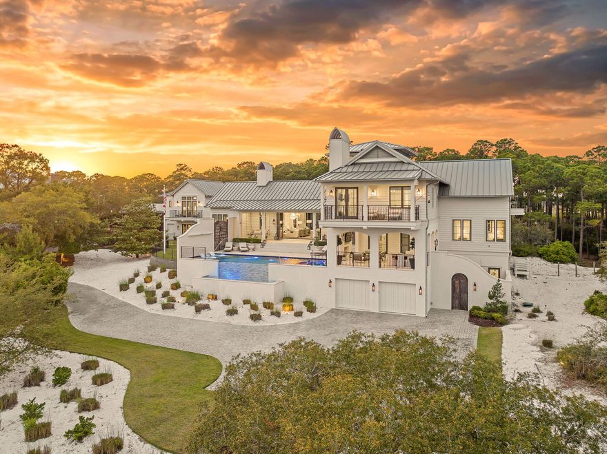 Tucked within the private, gated sanctuary of Four Mile Village, 285 Twisted Pine Trail presents an extraordinary opportunity to experience coastal living at its most serene and refined. Set on nearly three acres and bordered by the unspoiled beauty of Topsail Hill Preserve State Park, this remarkable estate offers a rare sense of privacy, where native wildlife and natural landscapes take center stage. From the moment you arrive, the canopy-lined drive evokes a sense of 'Old Florida,' a peaceful retreat far removed from the pace of everyday life.

One of the property's most exceptional features is its dual frontage, capturing both coastal dune lake and gulf views. Coastal dune lakes are among the rarest natural phenomena in the world, found in only a handful of locations globally... and this home enjoys sweeping vistas of Fuller Lake to the north and the gulf to the south.
Thoughtfully designed by Geoff Chick, the home blends timeless architecture with exceptional craftsmanship. Inside, curated details abound, from handcrafted lighting imported from Murano, Italy, to rich, rough-hewn cypress flooring that grounds the space in warmth and character. The expansive open-concept living and dining area is anchored by soaring vaulted ceilings, exposed beams, and a striking double-sided fireplace, all framed by walls of glass that capture panoramic water views.
The gourmet kitchen is both functional and elegant, featuring an oversized quartzite island, a full suite of Thermador appliances, and additional support spaces including a butler's kitchen, wet bar, and wine cellar, perfect for effortless entertaining. Retractable European doors seamlessly connect the indoors to multiple outdoor living areas, where covered porches, open-air decks, and an infinity-edge pool and spa create a resort-style setting overlooking the dunes and emerald waters beyond.
Each bedroom suite is designed as a private retreat, offering either lake or gulf views and uniquely crafted en-suite baths with custom tilework. The primary suite is a standout, complete with its own fireplace, private balcony, and a spa-inspired bath where both the soaking tub and shower overlook the gulf. Additional features include a third-level bunk room with a morning bar and a private elevator servicing all levels of the home.
A detached carriage house enhances the property with a first-level game room, wet bar, and golf cart garage, while the upper level provides a bright guest space with built-in bunks, a full bath, and sweeping views. Nearly 300 feet of lake frontage and a private dock further elevate the outdoor experience, offering direct access to one of the area's rare coastal dune lakes.
As part of Four Mile Village, residents enjoy access to over 230 acres of preserved coastal woodlands, a 40-acre dune lake, and more than 2,000 feet of private Gulf shoreline. Rich in both natural beauty and history, this one-of-a-kind property captures the essence of Northwest Florida's most treasured coastline, where luxury and untouched landscape exist in perfect harmony.