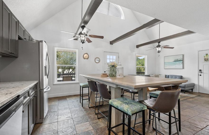 Turnkey and ready. Welcome to Dolphin Den -- a fully furnished 3BR/3BA coastal showpiece in the heart of Biltmore Beach, three blocks to sugar-white sand and 226 feet to the Dolphin Drive boat ramp. From the moment you arrive, the home's crisp white board-and-batten exterior, classic gabled roofline, and elevated wraparound deck capture the timeless Florida beach-cottage charm buyers dream about. Peek between the swaying palms and you'll catch glimpses of the bay just beyond -- your daily view from sunrise coffee to sunset cocktails.

The expansive elevated deck is the heart of outdoor living here: an alfresco dining set for four, a separate lounge area with cushioned seating, a grill ready for fresh catch, and room to entertain a crowd under the Gulf Coast sky. Inside: a main-floor king primary suite with double vanities and walk-in shower, an upstairs queen retreat, and a bunk room built for the kids. Open-concept living flows out to those bay views through every window. Stainless kitchen, smart TVs in every bedroom, 58'' living room screen, and a game room with two stand-up arcades.

Outside, mature palms and tropical landscaping frame a fully fenced corner lot with parking for four plus your boat, jet ski, or golf cart. Elevated construction means no flood insurance required -- along with no HOA, a 2020 roof, HVAC, and water heater, and a termite bond in place. The lower level beneath the home is plumbed and wired, ready to expand your square footage and your vision. Whether you're after a primary residence, a second home, or a proven short-term rental in one of PCB's most walkable beach neighborhoods -- Dolphin Den is the rare property that checks every box. Don't just buy a home. Buy the lifestyle.