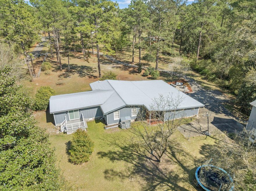 Welcome home to charm, space, and a touch of nature just 2 blocks from the beauty of Lake DeFuniak!
This 3 bedroom, 2.5 bath home offers oversized bedrooms and a thoughtfully designed layout with both comfort and functionality in mind. It is located on approximately 7.2 acres with a creek running through. The spacious primary suite features brand-new carpet, direct access to a private back deck through sliding glass doors, and a beautifully updated ensuite with a custom walk-in shower and double vanity. An added bonus: the large laundry room is conveniently located right inside the primary walk-in closet. Throughout the home, you'll find a blend of character and updates, including original hardwood flooring in select rooms and a welcoming formal dining area complete with a wood-burning fireplace (currently capped, but full of potential). The kitchen is well-equipped with real wood cabinetry, stainless steel appliances, a double oven, and a breakfast bar. There is also a large pantry/storage area. Off the double carport you will find the half bath, a storage room and another space currently being used as a home office. Enjoy the outdoors with frequent deer sightings, a brick-paver patio, a creek flowing through the property and a large two-story barn perfect for storage, hobbies, or future possibilities. This home is situated perfectly if you are one to enjoy your own quiet space with plenty of room to roam and also be close to town. It's a short distance to Lake DeFuniak as well as DeFuniak Springs Main Street Downtown area for dining and shopping options, among more! This home has been beautifully maintained and updated. Contact your favorite realtor to schedule a showing. Appointment only.