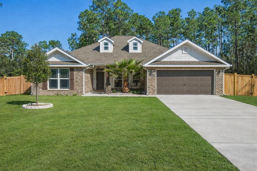 Welcome to this beautiful 4-bedroom, 2-bath home offering 2,008 square feet of living space in the desirable Navarre, Florida area just minutes from the beach and many popular local attractions. With great curb appeal featuring a brick exterior, bay windows, and a two-car garage, this home makes a wonderful first impression. Step inside to a bright and inviting open-concept layout that seamlessly connects the dining, living, and kitchen areas. Large rear windows fill the space with natural light and overlook the private, fully fenced backyard. The spacious kitchen is perfect for everyday living and entertaining, featuring a large granite island with bar seating, stainless steel appliances, pendant lighting, ample cabinetry, a built-in microwave, farmhouse-style sink, and both an eat-in breakfast area and a separate dining space. The primary suite offers a relaxing retreat with a tray ceiling, ceiling fan, and windows overlooking the backyard. The ensuite bathroom includes dual vanities, a custom-tiled walk-in shower with glass door, a separate soaking tub, and a large walk-in closet. Secondary bedrooms are generously sized and provide plenty of closet space. The additional bathroom features granite countertops and a spacious layout. A well-appointed laundry room includes extra storage space for added convenience. Step outside to enjoy the fully fenced backyard complete with a covered patio for grilling and entertaining, as well as a cozy fire pit area perfect for relaxing evenings. Located near top-rated schools, beautiful Gulf Coast beaches, and the best that Navarre has to offer, this home provides the perfect blend of comfort, convenience, and coastal living. Schedule your showing today and come experience the Florida lifestyle!