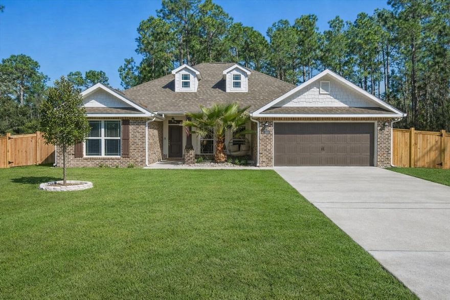 Welcome to this beautiful 4-bedroom, 2-bath home offering 2,008 square feet of living space in the desirable Navarre, Florida area just minutes from the beach and many popular local attractions. With great curb appeal featuring a brick exterior, bay windows, and a two-car garage, this home makes a wonderful first impression. Step inside to a bright and inviting open-concept layout that seamlessly connects the dining, living, and kitchen areas. Large rear windows fill the space with natural light and overlook the private, fully fenced backyard. The spacious kitchen is perfect for everyday living and entertaining, featuring a large granite island with bar seating, stainless steel appliances, pendant lighting, ample cabinetry, a built-in microwave, farmhouse-style sink, and both an eat-in breakfast area and a separate dining space. The primary suite offers a relaxing retreat with a tray ceiling, ceiling fan, and windows overlooking the backyard. The ensuite bathroom includes dual vanities, a custom-tiled walk-in shower with glass door, a separate soaking tub, and a large walk-in closet. Secondary bedrooms are generously sized and provide plenty of closet space. The additional bathroom features granite countertops and a spacious layout. A well-appointed laundry room includes extra storage space for added convenience. Step outside to enjoy the fully fenced backyard complete with a covered patio for grilling and entertaining, as well as a cozy fire pit area perfect for relaxing evenings. Located near top-rated schools, beautiful Gulf Coast beaches, and the best that Navarre has to offer, this home provides the perfect blend of comfort, convenience, and coastal living. Schedule your showing today and come experience the Florida lifestyle!