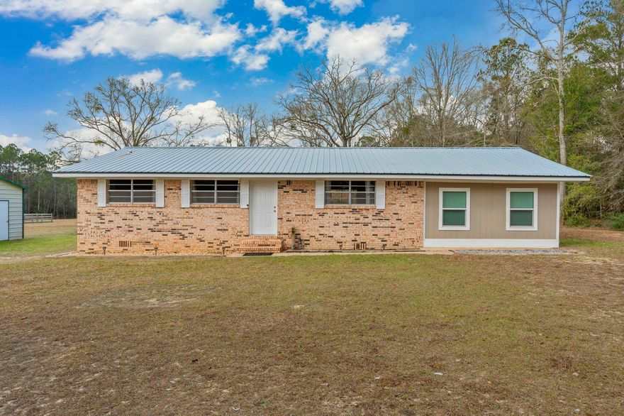 Welcome home to peaceful country living just minutes from everything you love! Ideally located less than two miles from both beautiful Lake DeFuniak and the charming shops and restaurants of Downtown DeFuniak Springs, this brick home offers the perfect blend of privacy, space, and convenience.
Situated on 2.5 acres of manicured land, the property immediately impresses with its brand-new covered back deck overlooking your expansive backyard. The fenced-in yard features raised garden beds ready for planting The large enclosed barn provides excellent storage and workshop potential. The lean-to  provides covered parking for equipment and recreational vehicles.
Inside, you'll find 4 bedrooms and 1 beautifully renovated bathroom, completely updated from top to bottom with modern finishes. The spacious kitchen offers abundant cabinet storage and flows seamlessly into a dedicated dining area and living room--perfect for everyday living or entertaining.
The fourth room adds valuable flexible space and can serve as a fourth bedroom, home office, hobby room, or additional storage area. The oversized primary bedroom provides plenty of room for a cozy sitting area or workspace and includes a generous walk-in closet.
Additional highlights include a durable metal roof that's only 12 years old, offering peace of mind for years to come. The interior of the home has also been completely repainted.