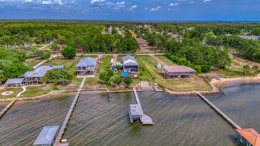 Bay Front home offering 3 bedrooms, 2.5 bathrooms, and a bonus mother-in-law suite. Experience refined coastal living in this beautifully reimagined luxury waterfront home of 2,034 square feet, all set on an expansive 0.81-acre lot with breathtaking west-facing views over Escambia Bay. Completely remodeled from top to bottom in 2023, this property offers relaxed elegance.

The main level showcases a thoughtfully expanded kitchen featuring new cabinetry, countertops, flooring, and appliances, along with a walk-in pantry and a stylish wet bar/beverage center. A newly added laundry room enhances convenience, while custom trim, fresh paint, solid wood interior doors, and updated finishes elevate the home's overall design. The open living spaces flow seamlessly to two screened-in porches-- to two screened-in porches--on both the main and lower levels--where you can take in stunning sunsets over the water.

The spacious primary and guest accommodations are complemented by a versatile lower-level bonus mother-in-law suite, complete with a kitchenette, full bath, and washer/dryer--ideal for guests, extended family, or additional living space. The lower level also includes a 2-car garage with generous storage.

Outdoors, this property truly shines. Enjoy direct waterfront access with a bulkhead, dock, boathouse, and boat lift equipped with electric and water. A walk-in beach area and stone fire pit create the perfect setting for evenings by the bay, while the above-ground saltwater pool with deck and grill area offers a private oasis for relaxing or entertaining. The expansive grounds also feature a new concrete driveway with a pickleball court and two RV sites with full hookups (electric, water, and sewer).

Additional upgrades include conversion from septic to city sewer with a grinder pump system, upgraded electrical service with new meter socket and breaker panels, and enclosure of the first floor for expanded functionality. With no HOA and excellent potential for short-term rental income.