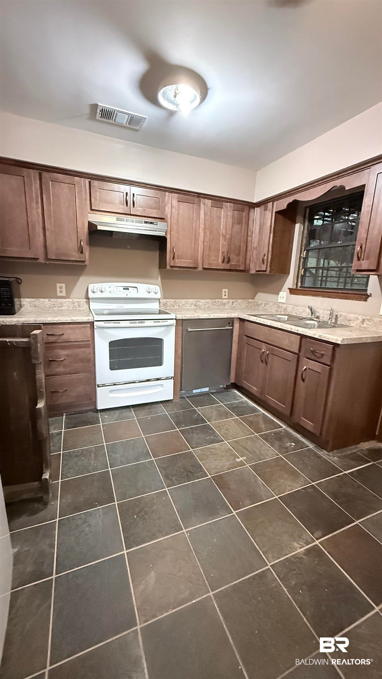 Kitchen with white range with electric stovetop, dishwasher, under cabinet range hood, and dark brown cabinetry
