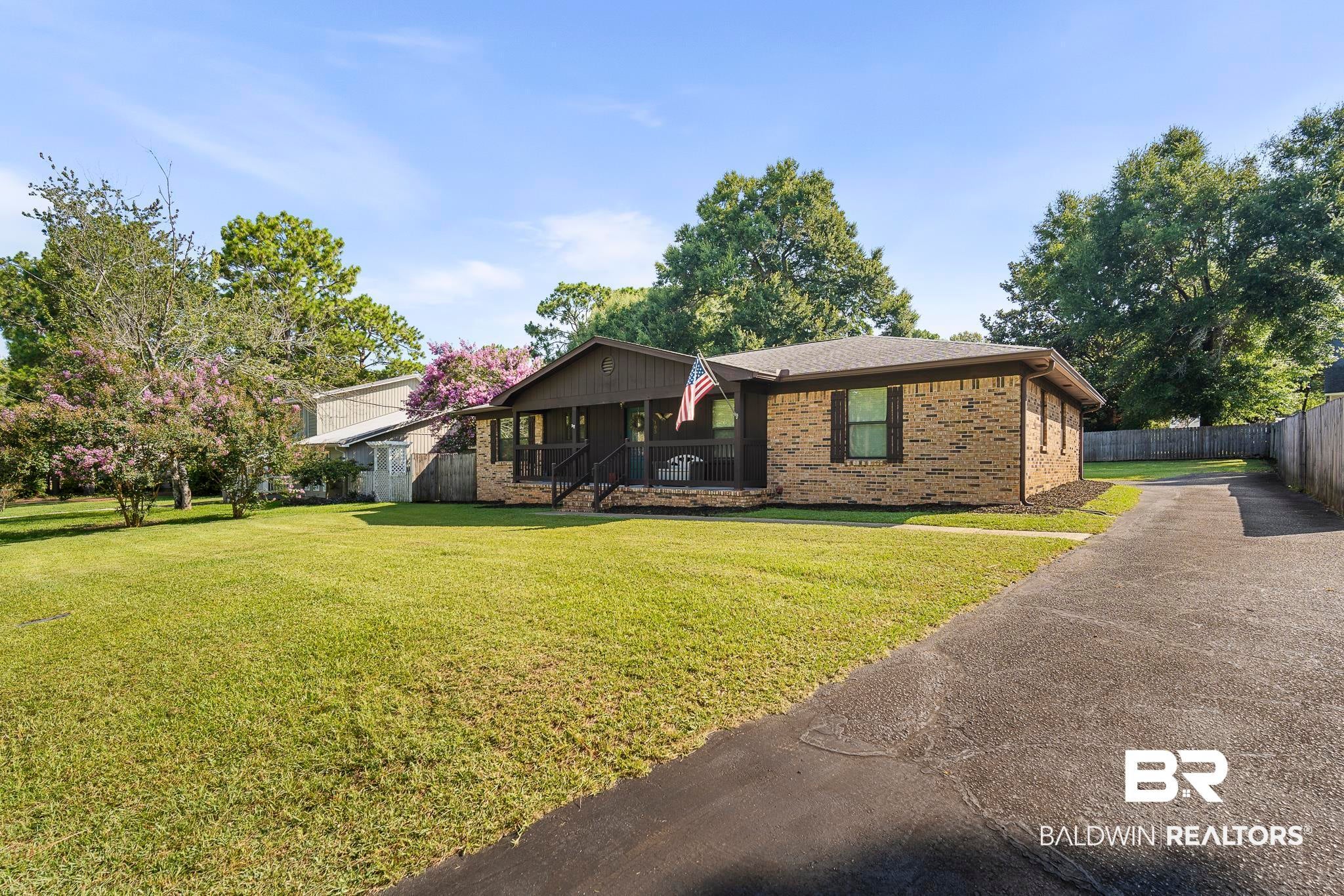 Brick exterior with dark shutters, covered front porch, and mature landscaping