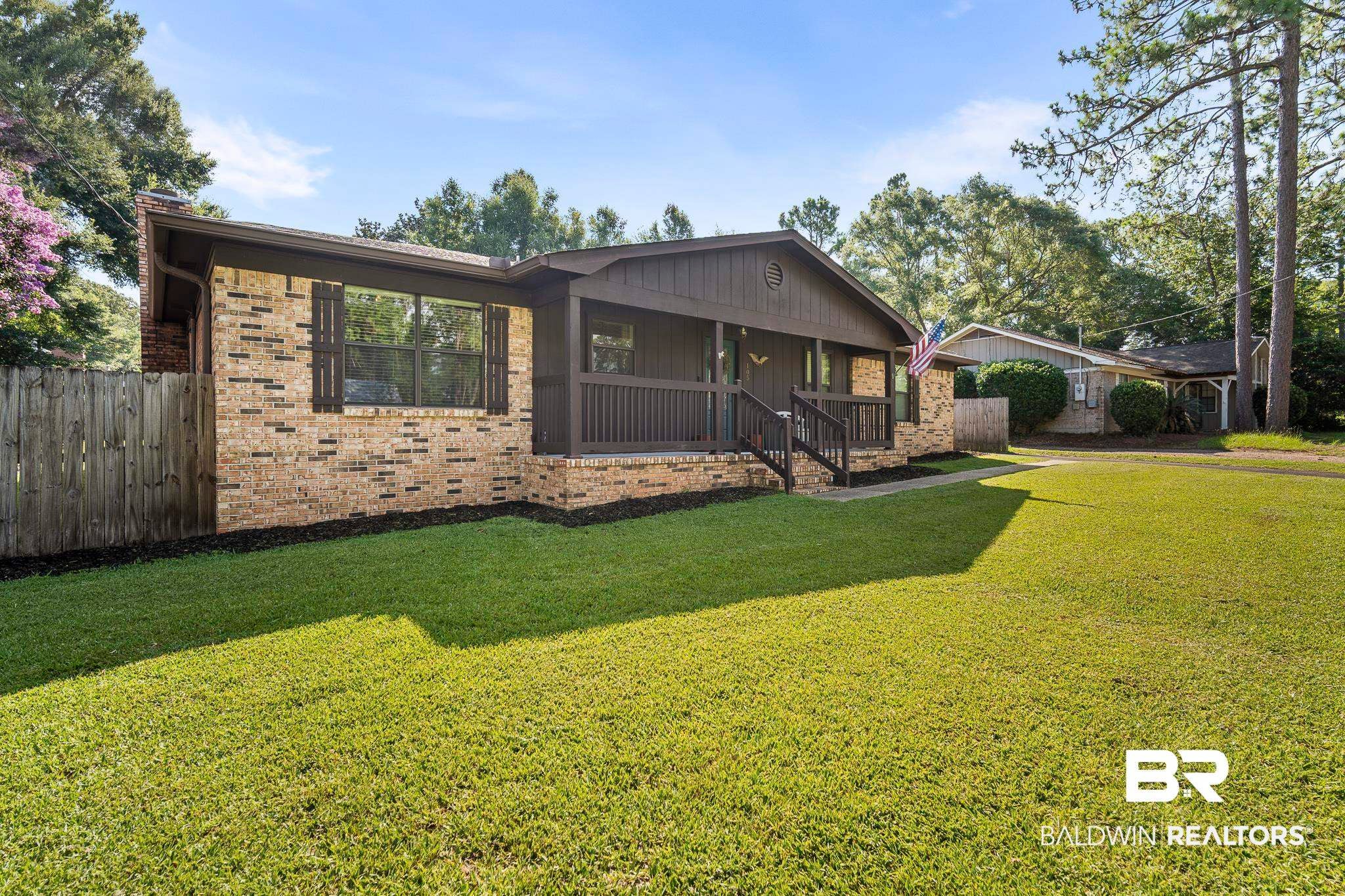 Brick exterior featuring a covered front porch with dark wood railings and stairs