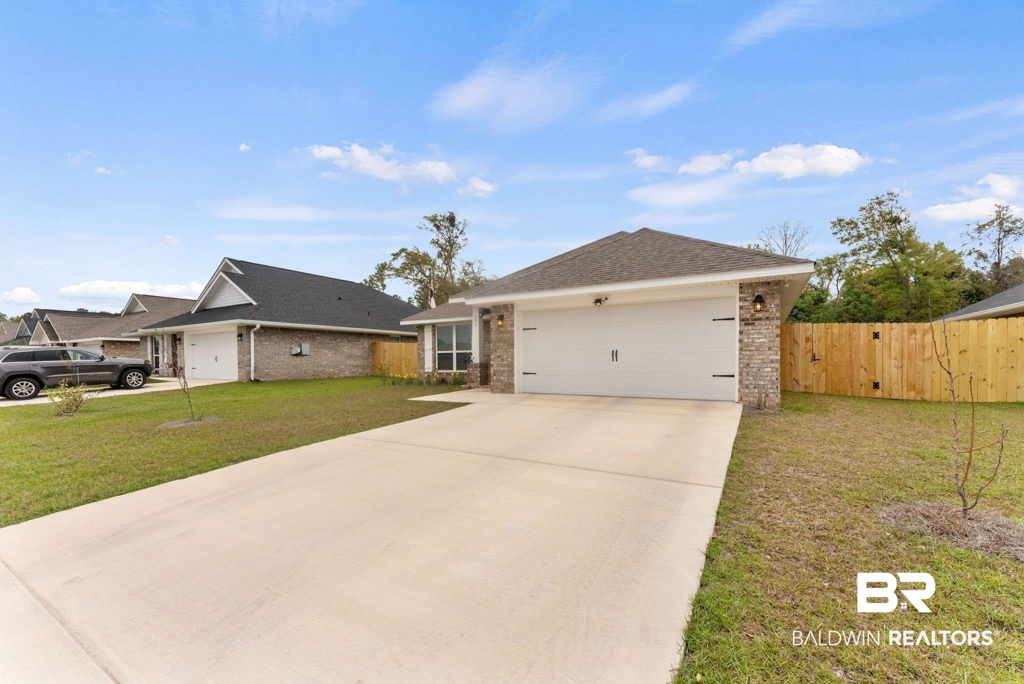 Ranch-style house featuring a garage, driveway, brick siding, and roof with shingles