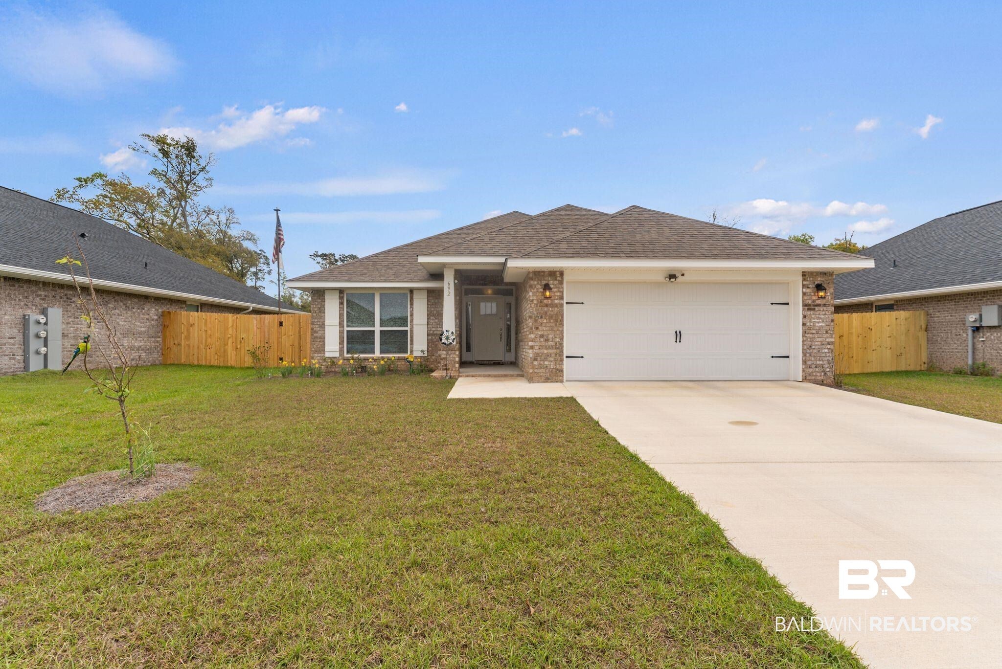 Single story home with a shingled roof, a garage, a front yard, and brick siding