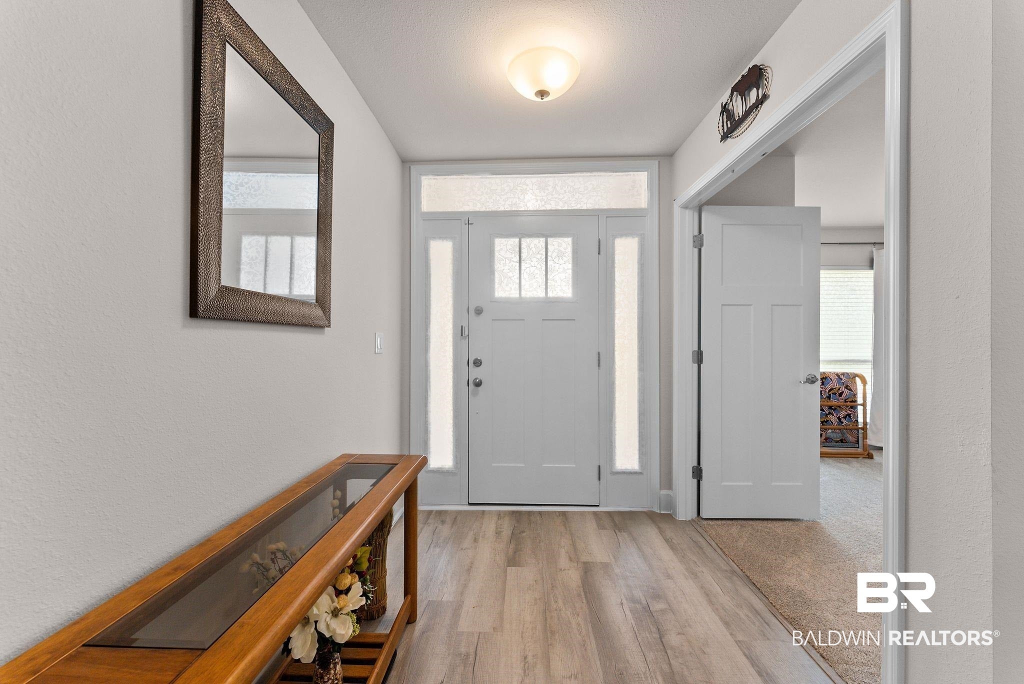 Doorway to property featuring brick siding, roof with shingles, and a porch
