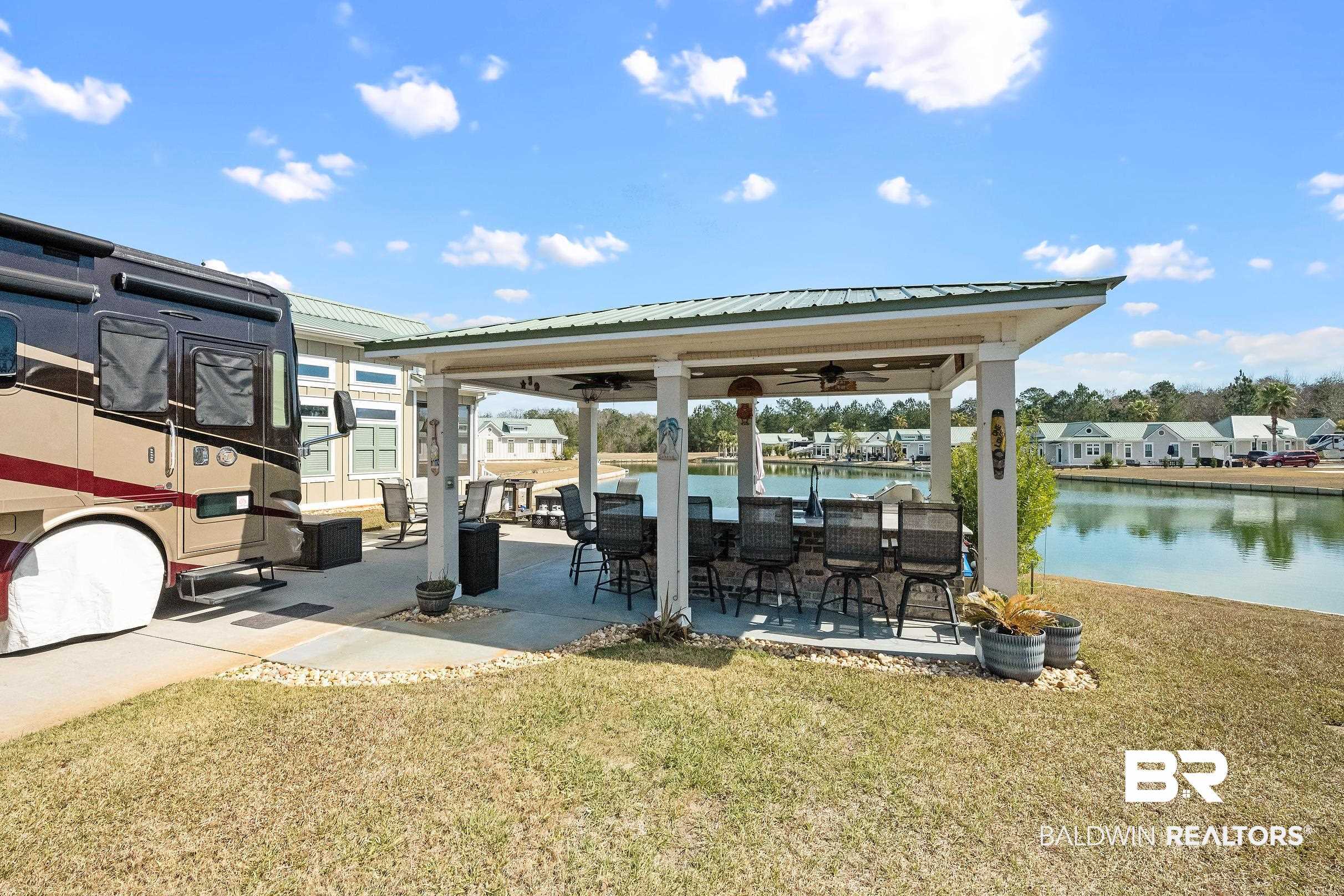 Dock featuring a patio, a lawn, a gazebo, a water view, and an outdoor bar