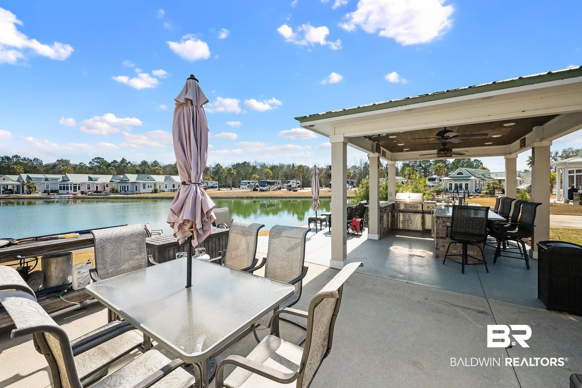 View of patio featuring a ceiling fan, a residential view, an outdoor kitchen / dining area, and a water view