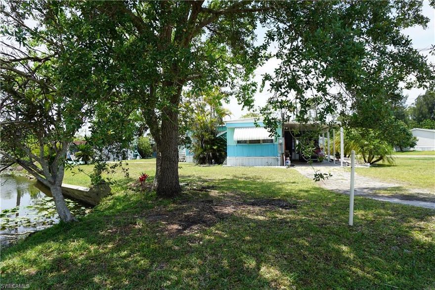 NEW PRICE NOW UNDER $135,000 ON YOUR OWN LAND! NO HOA! Make this your new Southwest Florida address! Located in South Punta Gorda, this very affordable manufactured home resides on a generously sized corner waterfront lot (100 x 125), where the land is owned outright—there is no lease and no mandatory homeowners' association. Bring your boat or RV and park next to the home. This quaint residence features 2 bedrooms and a bonus room addition with separate entrance and bathroom (could make it a family room or an in-law suite), and a 2-car carport. The home comes partially furnished including a complete kitchen appliance package, a washer, dryer, and an additional refrigerator. The enclosed lanai/Florida Room provides extended living space. Additionally, the back yard contains two newer sheds: one houses the well equipment and a generator, and the other includes a workbench along with storage space for yard equipment. The property's back yard retreat allows residents to enjoy views of the freshwater canal populated by fish and turtles, as well as tropical landscaping that surrounds the home. An avocado tree on the premises offers fresh seasonal produce. Conveniently located near an I-75 interstate exit and Punta Gorda Airport/Allegiant Airlines, and the property is approximately 30 minutes from Fort Myers – Southwest Florida International Airport. Nearby amenities include golfing, pickleball, downtown Punta Gorda shopping, farmer’s markets, parks, boat ramps, and a wide culinary variety of restaurants.