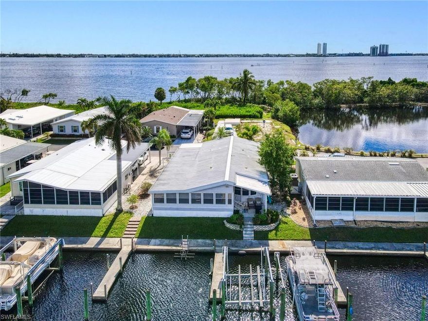 One of the BEST lots just around the bend from the river in the highly sought-after 55+ community of Old Bridge Village! This well maintained 2BR waterfront, Gulf-access home features impact windows, a spacious air-conditioned Florida room, plantation shutters, beautifully updated kitchen and baths, and professionally designed furnishings that are all included. Step outside and enjoy true Florida living—watch manatees and dolphins play from your backyard, cast a line from your private dock, or store your boat on the lift and be in the river within minutes. This hidden-gem, gated community offers a relaxed coastal vibe and an impressive array of amenities including pickleball, tennis, and basketball courts, two community pools, a fitness center, and an active clubhouse with a full calendar of social events and activities. Ideally located just minutes from Downtown Fort Myers River District, shopping, dining, airports, and everything you need to enjoy your retirement years in comfort and style.