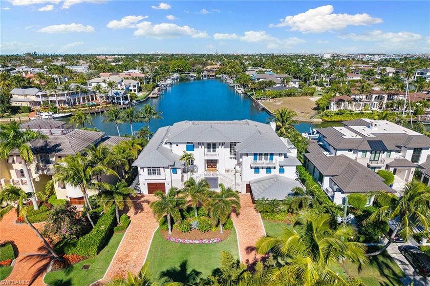 Views, Views, Views! An unparalleled expression of coastal grandeur, this extraordinary waterfront estate showcases luxury living in the heart of Aqualane Shores, one of Old Naples prestigious neighborhoods, just minutes to the Gulf of Mexico, a short distance to the beach and downtown’s historic Third Avenue South. Positioned along one of the community’s widest canals, this architectural masterpiece captures the essence of Old Naples elite lifestyle, where timeless design, masterful craftsmanship and effortless elegance converge. A boater’s and car collector’s dream, the 6,130-square-foot residence seamlessly blends old Florida charm with refined sophistication, highlighted by exquisite millwork, rich hardwood flooring, shiplap accents and tranquil water views throughout the home. Designed for grand entertaining and intimate gatherings, the open-concept layout features a dramatic two-story great room, a gourmet kitchen with dual islands, and a spacious family room flowing naturally to a covered lanai with outdoor kitchen, pizza oven and fireplace. The primary suite, on the main level, affords the utmost privacy and elegance, featuring dual dressing areas and an adjoining study that easily transitions into an additional guest suite when desired. A separate guest residence, reached by private elevator, offers a full kitchen and living area, ideal for extended stays or hosting with complete independence. Among the home’s many refined appointments are a temperature-controlled 500-plus bottle wine room, a stylish wet bar, a secure safe room and an impressive 12-car garage designed for the connoisseur of fine automobiles. Outside, the resort-inspired grounds unfold with a waterfront vanishing-edge pool, spa, putting green and a private boat slip with a 34,000-pound lift offering seamless, bridge-free navigation from your backyard to the open Gulf of Mexico, where turquoise waters and endless horizons await, completing this extraordinary tropical retreat.