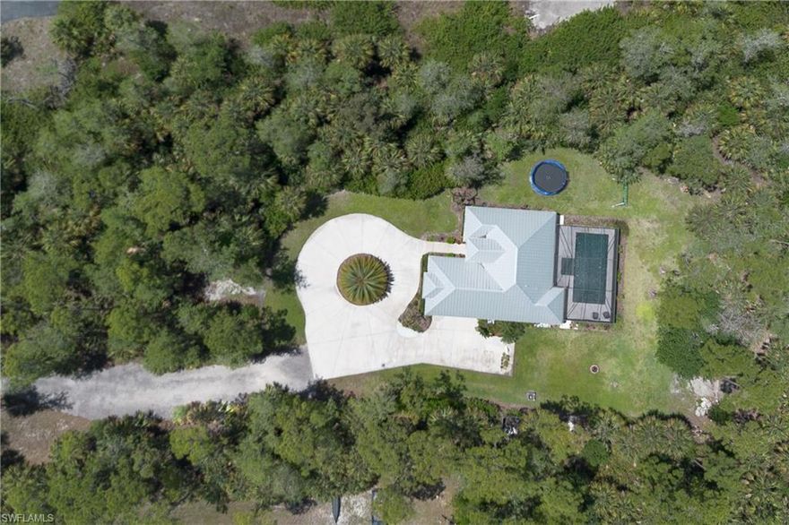 Discover your own private oasis in this 2018 custom-built estate, perfectly situated on a sprawling 2.73-acre gated lot. Whether you are looking for a serene retirement sanctuary, a seasonal getaway, or a permanent residence, this cottage-style home offers the perfect blend of modern sophistication and ultimate security.  
Step inside to a bright, airy floor plan, featuring tall tray ceilings and expansive windows that bathe the home in natural light. The split-bedroom layout ensures maximum privacy, complemented by high-end finishes including:
Flooring: Timeless porcelain wood-plank tile throughout. Gourmet Kitchen: Pristine white shaker cabinetry, premium quartz countertops, an oversized social island, and high-performance LG stainless steel appliances. 
Water Quality: Peace of mind with an advanced whole-home Reverse Osmosis filtration system.  The Ultimate Outdoor Retreat with the backyard is a masterclass in Florida living. Relax by the stunning 15x33 pool and spa built in 2023, featuring shimmering glass tiles and a premium screen enclosure. Automation with Fully controlled via Pentair equipment and the Aqualink remote or via app on your phone. You'll love the ambiance color-changing lighting, elegant deck jets, and luxurious Royal Marble decking.  Professionally landscaping upgraded with St. Augustine sod, new irrigation, and integrated side-yard drainage.  Fortress-Level Construction & Security
Built to exceed expectations, this home remained completely undamaged by Hurricane Ian due to its heightened elevation and superior protection: Impact-Rated: Full impact windows and doors, plus an electric hurricane shutter system on the lanai. The durability of the Long-Lasting metal roof and energy-efficient spray foam insulation.  Privacy and secured by a sophisticated $50,000+ custom fence and gate system.  Space, Freedom & Location with no HOA fees or restrictions, you have the freedom to truly make this estate your own.  Storage galore with A 300-foot+ driveway leads to a 2-car garage with epoxy flooring, offering ample room to park your RV or boat.  Plenty of acreage remains to build additional structures or expand the square footage of the existing structure.  Lifestyle and amenities located just 2 minutes from Big Corkscrew Island Regional Park, this 150-acre regional park features the county's largest playground, a massive aquatic complex with waterslides and competition pools, and a 22,641-square-foot community center. Visitors can also enjoy an event lawn with a stage alongside extensive sports facilities, including courts for pickleball, tennis, and basketball, plus multiple turf fields and softball diamonds.