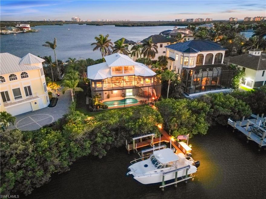 Stunning home nestled on a tranquil peninsula in the double-gated Southport on the Bay in North Naples’ premier community of Barefoot Beach offers breathtaking bay views from nearly every window. A true paradise for boaters and beach lovers, this property boasts direct Gulf-access in minutes (no bridges) and is just a short 5-minute walk to the pristine shores of Barefoot Beach. Designed for the ultimate waterfront lifestyle, this home features a private boat dock, dual boat lifts with 16,000 lb and 10,000 lb capacities, and a dedicated fish cleaning station for avid anglers. Inside, you’ll find 4 spacious bedrooms, tile flooring, wood flooring (Bamboo), and gorgeous wood-paneled ceilings. The home is equipped with brand-new hurricane impact windows (2025), hurricane shutters, new hurricane garage doors (2022), new HVACs, new water heater, and offers a dedicated space to add an elevator. Additional features include a versatile ground-floor flex space and a newly epoxied garage that can accommodate 4+ cars. Outside, step into your own outdoor haven, complete with a summer kitchen ideal for al fresco dining while soaking in breathtaking bay views. Perfect for entertaining, the expansive lanai features a brand-new picture screen enclosure, a newly resurfaced pool, an outdoor shower, stone waterfall, and a bar area. The beautiful chef’s kitchen features white cabinetry, soft close cabinets, granite countertops, stainless steel appliances, an eat-in area, and a breakfast bar for casual dining. The primary suite serves as a private retreat with its own balcony overlooking the water, and a spa-like bathroom complete with dual vanities, a glass-enclosed shower, and a separate jetted tub. Conveniently located near fine dining, RSW Airport, Mercato, and Waterside Shops, and just 15 miles from the renowned Fifth Avenue in Naples, this home is a true gem in the heart of Southport in Barefoot Beach.