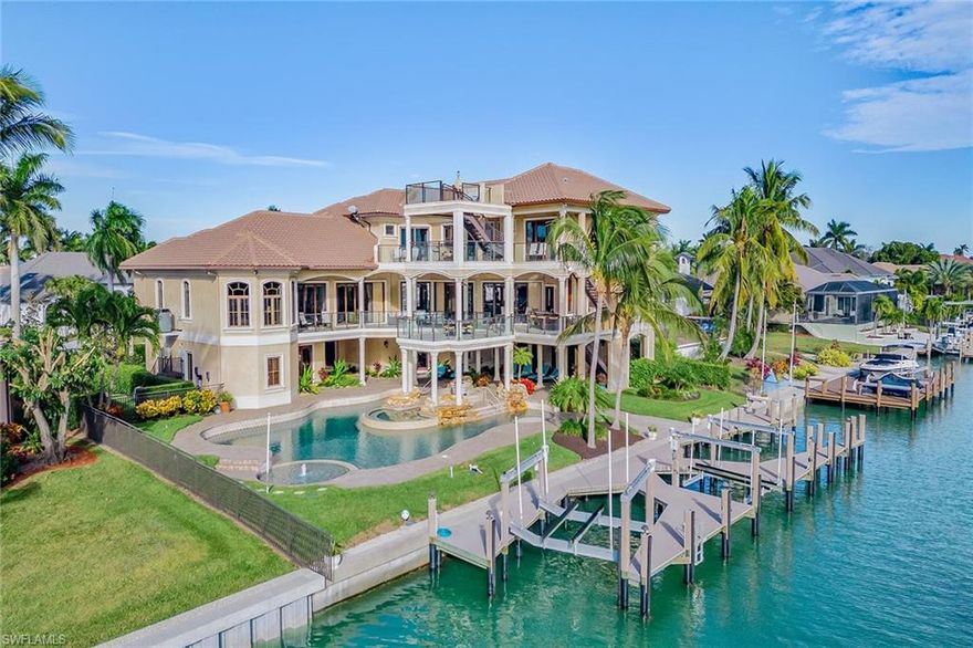 On the south side of Caxambas Court in Marco Island's prestigious Estates neighborhood, this exceptional three-story waterfront estate epitomizes luxury coastal living. Boasting 125 feet of deep-water frontage, the property offers direct Gulf access and panoramic southern views, further enhanced by a unique fourth-floor observation deck. Encompassing 6,370 square feet of air-conditioned space and totaling 11,679 square feet under roof, this residence features five bedrooms, an office, a theater, and five full and two half baths, all meticulously designed with the finest materials and craftsmanship. Inside, soaring coffered ceilings, intricate three-piece crown molding and travertine flooring create an atmosphere of refined elegance. The gourmet kitchen is a chef’s dream, equipped with custom wood cabinetry, granite countertops, dual center islands, a seven-seat breakfast bar and top-of-the-line JennAir appliances, including a six-burner gas range and double wall ovens. The great room features a mosaic tile accent wall, built-in gas fireplace and custom bookcases, seamlessly connecting to the expansive lanai through glass sliders. The owner's suite serves as a private sanctuary, offering a tray ceiling, walk-in closet and a spa-like en-suite bath with dual custom vanities, an open walk-in shower with multiple heads, a jetted soaking tub and dual water closets with a bidet. Each guest suite is thoughtfully appointed with tray ceilings, walk-in closets and en-suite baths, ensuring comfort and privacy for all. The state-of-the-art theater room, complete with a wet bar, surround sound and built-in projector cabinetry, provides an ideal space for entertainment. The exterior is equally impressive, featuring a fully fenced backyard, four balconies, impact-resistant doors and windows, and a stamped concrete circular driveway. The outdoor living area includes a heated saltwater pool with spa, an outdoor kitchen equipped with a Fire Magic gas grill and mini refrigerator, and a gas fire pit surrounded by a tranquil fountain. Boating enthusiasts will appreciate the private composite dock with a captain’s walk, two Hi-Tide boat lifts and a 40-foot slip with provisions for a 30,000-pound lift, offering unparalleled access to the Gulf. Modern conveniences abound, including a private elevator, in-ceiling speakers, a video security system, Honeywell 240V central vacuum, two Rinnai tankless water heaters, a Generac 48-kilowatt whole-home generator and a 1,000-gallon propane tank. The six-car air-conditioned garage is outfitted with built-in storage cabinets, a workbench and a gym area, catering to automotive enthusiasts and fitness aficionados. This remarkable estate seamlessly blends luxury, comfort and cutting-edge technology, offering an unparalleled coastal lifestyle in one of Marco Island’s exclusive enclaves.