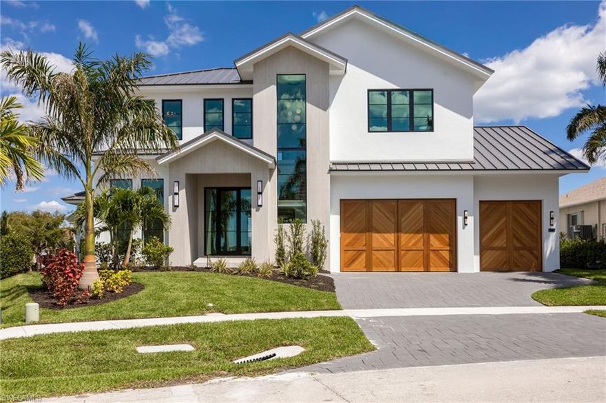 NEW CONSTRUCTION Indulge in the pinnacle of coastal luxury with this brand-new, custom-built Emerald Building Group designed masterpiece perfectly positioned near Marco Island's premier shopping, dining, and world-renowned white-sand beaches. Designed to impress at every turn, this contemporary waterfront residence delivers 4 bedrooms, 6 bathrooms, an office/den, and 3,923 sq.ft. of A/C living space--all wrapped in timeless craftsmanship and modern elegance. Step inside to soaring 12-ft ceilings and a dramatic 10-ft wall of windows that frame wide waterway views, flooding the home with natural light. Throughout the main level, white oak flooring, 10-ft impact glass sliders, and a double entry glass front door create an atmosphere of openness and refined sophistication. A striking architectural focal point, the custom white oak cantilever staircase with glass railings, sets the tone for this modern coastal retreat. The home features fully custom cabinetry, including floor-to-ceiling installations designed for both beauty and functionality. The first-floor primary suite is a serene haven with its own covered terrace featuring a custom gas ball fireplace--perfect for unwinding with tranquil waterfront breezes. The spa inspired bathroom offers a zero entry walk in shower, luxurious soaking tub, a dramatic floor to ceiling large format tile feature wall, fluted white wash oak double vanity, and custom closets designed for boutique style organization. Each guest suite is a private retreat, beautifully appointed with designer tiles, custom vanities, luxury finishes, and built-in closet systems, ensuring every visitor enjoys an elevated experience. Perfect for culinary enthusiasts, the gourmet kitchen showcases a designer appliance package with cabinet-panel fronts, expansive custom cabinetry, and a spacious island ideal for entertaining. A large walk-in pantry with additional appliances, a deep sink, and generous prep space enhances functionality. Upstairs, an entertainment lounge with a wet bar opens to a private balcony and sundeck, offering panoramic water views and the perfect setting for sunset gatherings. Designed for year-round coastal living, the expansive outdoor space includes: two large covered outdoor living areas with wood-detailed ceiling treatments, a spectacular lap pool with sun shelf and hot tub, large-format neutral stone pool deck, and a fully equipped outdoor kitchen. Exterior Features include: New seawall on a wide waterway, oversized 3-car garage with custom herringbone doors, impressive large-format stone façade, paver driveway and standing seam metal roof, hurricane-rated impact windows, doors, and garage doors, and 500-gallon propane tank. Just minutes to upscale shopping, fine dining, and Marco Island's breathtaking beaches, this residence offers the perfect blend of luxury living and island convenience--an extraordinary opportunity in one of Southwest Florida's most desirable coastal communities.
