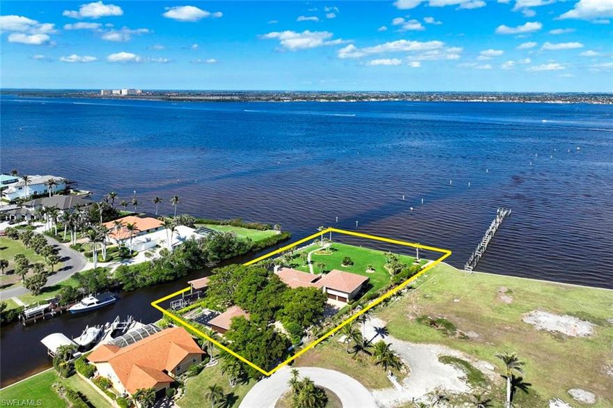 If you are looking for a peaceful haven to indulge in boating, gardening, hobbies that need plenty of space or simply seeking a place to relax and unwind, this is the perfect spot for you! A rare opportunity to own 1.25 Acres on the Caloosahatchee with 180+ feet of river frontage and 200+ feet on a canal. When you enter this estate property, you will be greeted by lush landscaping, majestic trees and pathways-a tranquil, nature sanctuary. The main living area has panoramic views of the river. A stone fireplace, built-in bookcases and gorgeous tongue and groove wood paneling add to the comfort of the living room. Entertaining family and friends is a breeze with many dining options, both inside and out, all enhanced by the beauty of the river. The primary bedroom is light and bright with sweeping water views and French doors that open to a private balcony. It is a spacious room with volume ceilings and a sitting area.  The primary bath has dual sinks, a walk-in shower and a walk-in closet/dressing room. This well-planned primary wing also features its own elevator and the conveniently located laundry. All bedrooms are ensuite. The ground level boasts an additional family room, with a stone fireplace, that walks out to the pool and screened patio, a full bath, a flex room that can be used for guests or hobbies, and an elevator to the main living level. A covered dock with water, electricity, an additional boat lift and an oversized dock deck are located on the canal. The car enthusiast or hobbyist will love the seven garages, three of which are in a free standing garage, currently being used as a workshop. This exceptionally well-built home has storm protection on all openings and a Briggs and Stratton whole house generator. Cool off in your private pool or bask in a myriad of outdoor living areas where you can enjoy balmy breezes off the river and spectacular sunsets. This is an investment that your family will enjoy for decades!