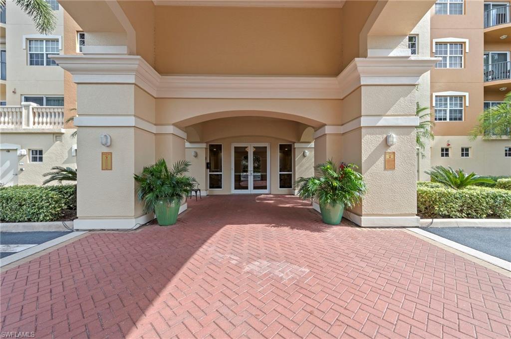 Entrance of Vista Pointe residence in Naples, featuring a covered entryway with brick pavers, decorative planters, and gated access, highlighting luxury living in a serene community.