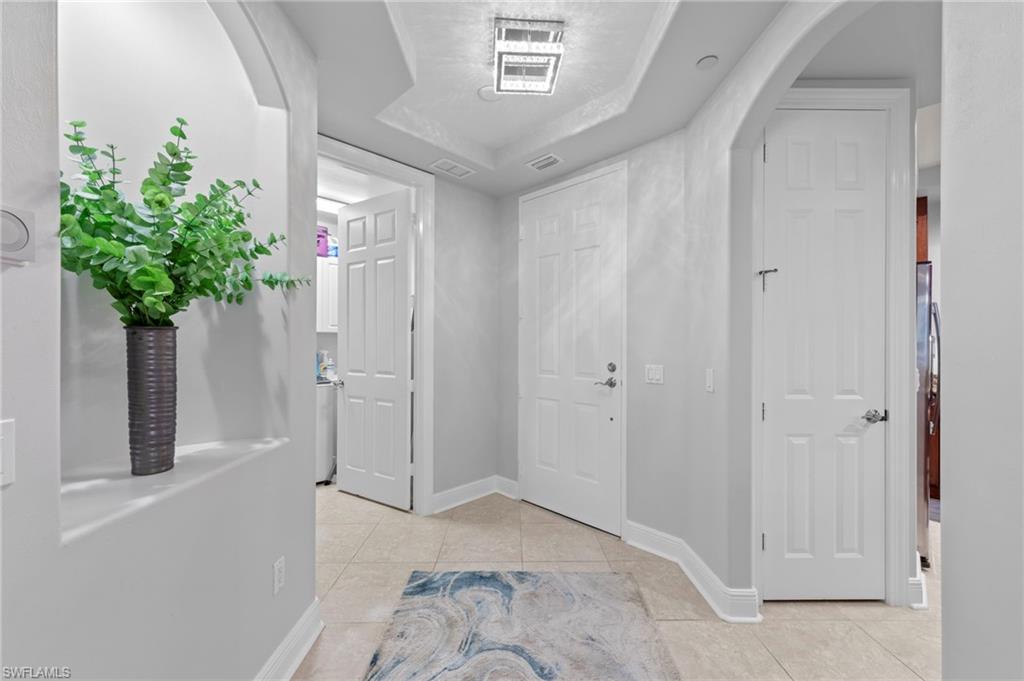Elegant entryway of a luxury residence in Vista Pointe, featuring a decorative plant in a tall vase, light-colored walls, and a spacious layout leading to doorways and a laundry area, emphasizing the sophisticated design and comfort of the home.