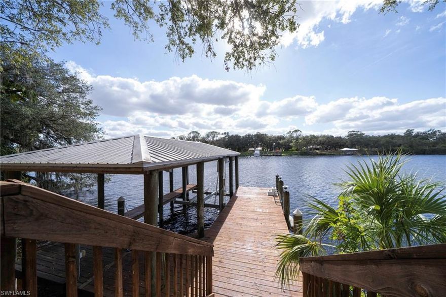 Discover a sanctuary of architectural brilliance and maritime excellence on this private Caloosahatchee Riverfront estate, offering refined living on an expansive 1.24-acre lot. Tucked behind a top-of-the-line, high-security gate, a winding drive through mature flowering trees leads to this cedar home that seamlessly blends modern sophistication with tropical warmth. This 3-bedroom, 3.5-bathroom masterpiece is offered fully furnished. The interior is a triumph of design, featuring soaring high ceilings and walls clad in rich, hand-finished wood that exude organic elegance. The expansive great room, anchored by a cozy fireplace, provides a grand setting for entertaining, framed by panoramic river views. For the culinary enthusiast, the chef’s kitchen is a masterclass in style, outfitted with professional-grade appliances, sleek cabinetry, and premium surfaces.
Designed for the discerning international buyer, the property includes a fully independent first-floor suite. This luxurious space functions as a private mother-in-law residence, complete with its own kitchenette, living area, and direct garden access. The boating complex features a boathouse with a 29’ lift, plus deep-water dockage for a 44’ to 60’ yacht. With rapid Gulf access and total privacy, this turn-key estate is the ultimate Florida sanctuary. Experience the rare intersection of elegance, security and nautical freedom.