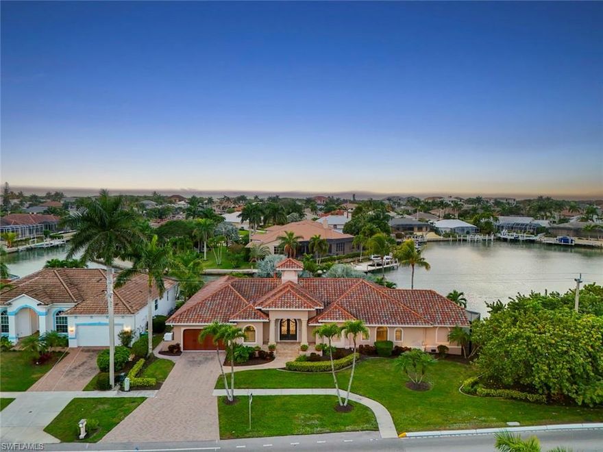 Set on a rare, oversized tip lot, this Marco Island residence offers long, sweeping bay and canal views with indirect Gulf access—and just one bridge between you and open water. With a southwest exposure, the home is perfectly positioned to catch the glow of afternoon light and enjoy unforgettable sunsets that unfold across the water.

Offering nearly 3,500 square feet of living space, the home has been thoughtfully expanded over time, creating a distinctive footprint rarely found on Marco Island. The layout includes three bedrooms, a dedicated office or den, four full bathrooms, and a private sun room off the primary suite, allowing the home to live generously while maintaining separation and privacy.  Walls of new impact glass sliders line the rear of the home, blurring the line between indoors and out while placing the view front and center throughout the main living areas.

The updated kitchen opens seamlessly to the living and dining spaces, designed for both everyday living and effortless entertaining. The primary suite is an expansive retreat, featuring a private sun room and tranquil water views—an ideal setting for morning coffee or quiet evenings. Pocket doors throughout the home add architectural intention, while a custom front door sets a refined tone upon arrival.
Outdoor living is exceptional. A vast covered and screened lanai wraps the rear of the home and is accessible from every waterfront-facing room, centered around a heated in-ground pool. Mature, intentionally planted trees along the water’s edge create a sense of remarkable privacy, allowing the setting to feel both open and secluded.
A private dock provides easy access to Marco Island’s waterways and the Gulf beyond. Additional features include automatic shutters, new impact glass sliders, remote-controlled blinds in the primary suite, and no HOA restrictions—enhancing both comfort and freedom. Just two blocks from Tigertail Beach, the home offers the rare ability to enjoy both boating and one of Marco Island’s most beloved beaches within moments.

A rare opportunity offering sweeping water views, near-Gulf boating access, and close proximity to Tigertail Beach.
