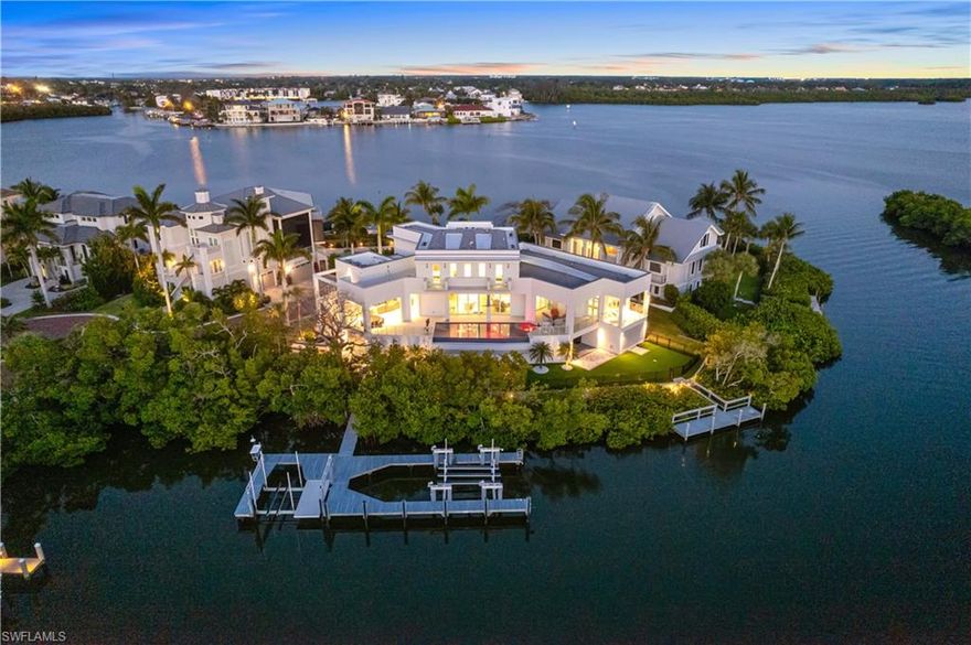 Nestled on a peninsula in North Naples’ premier community “Barefoot Beach,” this 2022 architectural marvel sits on one of the most desirable lots with an unrivaled 265 feet of wraparound water frontage for breathtaking Bay views on three sides of the home, direct Gulf-access & highly sought after Western exposure for endless Bayfront sunsets. A more impressive & breathtaking panoramic waterfront view cannot be found. This recently constructed contemporary masterpiece, located in the double-gated Southport on the Bay, comes from award-winning Potter Homes. Built like a fortress, this retreat offers all concrete construction and hurricane impact windows/doors. This is the ultimate beach & boaters’ delight with deeded beach-access a short walk-away & direct Gulf-access only 10 minutes from your dual boat docks/lifts. Every detail is meticulously crafted from the white oak flooring & inverted tray ceilings with custom lighting accents, to the chef’s kitchen with Thermador appliances & quartz waterfall countertops. Offers an incredible floor plan with 5 bedrooms, 5 baths, 2 half baths, dual laundries, private elevator, top-floor sundeck, 3 car garage & lower-level flex space. Fully pocketing sliders open to the outdoor oasis with an infinity pool/spa overlooking the beautiful bay, summer kitchen with a gas grill, refrigerator drawers & sink, 2 boat docks, 2 boat lifts & expansive fenced-in turf yard perfect for pets! Electric retracting screens on the Bayfront lanai allow both screened & open-air dining and entertainment. The primary bedroom is a tranquil haven with a private balcony, creating the ultimate secluded sanctuary. It includes a spa-like bathroom with a standalone tub, dual vanities & a spacious walk-in shower. Perfect for entertaining, the top level features a wet bar with a mini fridge, open-air sundeck with an exterior staircase to the private backyard paradise & 3 other guest beds with en-suites, walk-in closets & private balconies. An unparalleled opportunity-- the finest caliber of home in SWFL’s most beloved beach & boating community.