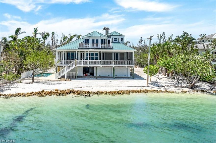 Luxurious bayfront pool home with captivating views and a private sandy beach! Beautifully designed beach house built in 2008, this special home has been a family retreat for the past 10 years. Only the finest finishes, including hand-scraped hardwood floors, custom millwork and casings, metal roof, and impact doors/windows. Main floor has a wrap-around porch with spectacular views. Kitchen overlooks the dining and living areas, with a large island, wine fridge and high-end Kitchen Aide appliances. Living room has a coffered ceiling and a fireplace encased by custom bookshelves. 2 guest bedrooms, each w/ ensuite baths and a separate office complete the main level. On the upper level, you'll find a primary bedroom with vaulted ceilings, an ensuite bath and bonus room that could be used as an office, craft, or exercise room. Expansive 180-degree views from the upper balcony! Lower-level garage is enclosed. Enjoy the convenience of an elevator that reaches all 3 floors! Many recent updates. EZ on and off the island nestled on a quiet dead-end street with other luxury homes. Start building your family island memories today!