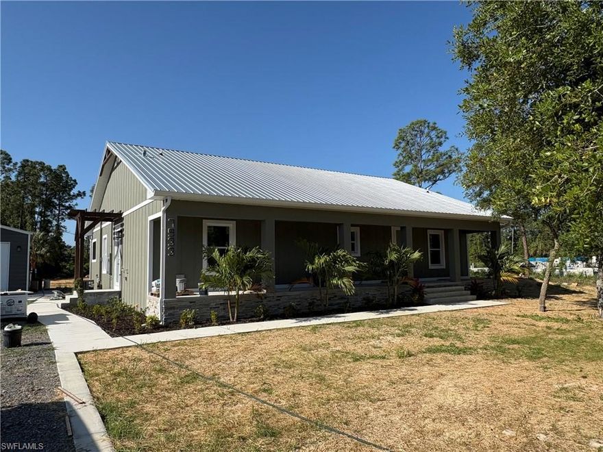 Welcome to your private slice of Southwest Florida living—where modern craftsmanship meets peaceful, wide-open space. This brand-new custom-built home sits on 1.25 acres, offering the perfect blend of privacy, functionality, and elevated design.

From the moment you arrive through the gated entry and long driveway, you’ll appreciate the thoughtful layout and curb appeal, complete with a spacious front porch ideal for relaxing and enjoying the natural surroundings.

Inside, the home showcases high-end custom finishes throughout, exposed wood beams, and a warm, inviting fireplace that anchors the main living space. The open-concept design flows effortlessly, featuring a beautifully designed kitchen with a farmhouse sink, granite countertops, and quality finishes that make both everyday living and entertaining feel seamless.

Durability meets efficiency with hurricane impact windows and doors, while LVP and tile flooring provide both style and easy maintenance throughout the home.

Step outside to your outdoor kitchen complete with wood plank ceilings, and a gas grill, perfect for hosting and enjoying Florida’s year-round lifestyle. The home has a 500-gallon propane tank, servicing the kitchen stove, hot water heater, and outdoor grill, adding both convenience and efficiency.

Car enthusiasts, hobbyists, or those needing extra storage will love the detached 4-car garage  of additional space ideal for boats, toys, a workshop, or all of the above.

This home is nearing completion  in just 2–3 weeks, giving buyers the rare opportunity to own a brand-new custom home without the long build timeline.

If you’ve been searching for new construction on acreage with upgraded finishes, functional space, and room to breathe—this is it.