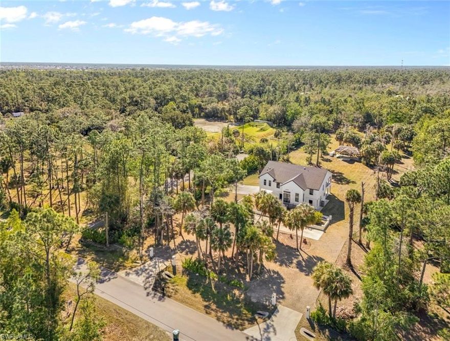 Discover your private retreat in the heart of Golden Gate Estates, featuring 2.14 acres of upland property within a sprawling 2.50-acre parcel — offering the perfect foundation to build, expand, and create your own tropical oasis. Here, serene privacy meets refined Florida living, with ample space to add a custom pool, guesthouse, workshop, or private mother-in-law suite. This new construction, never-lived-in two-story residence seamlessly blends modern luxury with the tranquility of expansive acreage. Boasting approximately 2,970 total square feet, the home showcases soaring volume and tray ceilings, elegant high-end finishes, impact-resistant windows and doors, tile flooring throughout, a new roof, new septic system, and a new hot water heater — delivering the peace of mind and energy efficiency today’s buyers expect from new construction. The open-concept design effortlessly connects the living, dining, and kitchen areas, creating an inviting space ideal for entertaining. At the heart of the home, the chef’s kitchen features a striking marble island with additional storage, custom white cabinetry, brand-new appliances, an electric cooktop, and generous prep space. Expansive sliding glass doors frame picturesque views of the lush grounds, flooding the interiors with natural light and enhancing the bright, airy ambiance. The primary suite serves as a private sanctuary, complete with balcony access overlooking the charming tiki bar, a spacious walk-in closet, and a beautifully appointed spa-inspired bath featuring dual vanities and an oversized walk-in shower with rainfall shower heads. Two additional bedrooms offer comfort, privacy, and ample closet space for family or guests. A wrap-around second-story balcony captures peaceful views of the surrounding landscape, while the expansive tiled lower level presents an exceptional opportunity — enclosing the first-floor space, including the garage area, could create approximately 3,000 additional square feet of living space. The fully finished lower-level garage already includes plumbing and tile work for a future bathroom, making it ideal for conversion into a private guest suite, home gym, or multigenerational living quarters. Outdoors, a concrete entertaining area and traditional tiki hut set the scene for unforgettable gatherings, perfectly embracing the relaxed elegance of Southwest Florida living — all within a brand-new estate designed for comfort, flexibility, and long-term value.