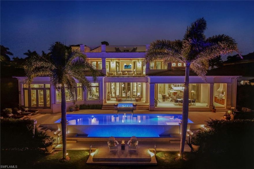 From the moment the front door opens, the bay becomes the focal point. Built by renowned BCB Homes, this custom estate was conceived to showcase the waterfront at every turn while delivering a level of detail and finish expected by the discerning buyer. The home unfolds through a thoughtful balance of formal and casual spaces, each designed to serve a purpose while maintaining visual continuity with the bay. Formal living and dining rooms create an elegant framework for entertaining, while everyday living naturally gravitates toward the family room, where expansive glass captures panoramic water views throughout the day. At center of the residence, the kitchen functions as a gathering space and a showpiece. Dual islands provide scale and flow, while marble countertops and professional appliances support serious cooking and entertaining. The 60-inch Wolf gas French plate range is not simply a feature but a statement, underscoring the home’s commitment to performance and design. Nearby, a dedicated bar and climate-controlled wine room anchor the home as a setting for evenings that linger. Inspired by coastal Europe, the home’s outdoor areas are anchored by an infinity-edge pool and spa that visually merge with the bay beyond. Covered and open-air spaces are layered to accommodate every part of the day, from shaded afternoons on the lanai to evenings around the summer kitchen and open sitting areas. The custom 90-foot dock extends the home’s lifestyle onto the water. Designed to blend naturally with its surroundings, it is equipped with a 16,000-pound lift and floating dock platform, ready to support aquatic adventures. The first-floor primary suite occupies a dedicated wing of the home with a bedroom positioned directly on the bay, offering sweeping water views upon waking and retiring. Dual walk-in closets and a marble-clad bath evoke the best European spas, while a secluded sitting room or office provides a quiet place to work or reflect. The first floor also features a beautifully finished billiards room or fifth bedroom, complete with its bath, allowing the home to adapt effortlessly. The second floor, with its dedicated elevator, features three beautifully appointed guest suites, each with a private en-suite bath. A central social room with a morning bar creates a natural gathering point for guests, reinforcing the home’s sense of ease and hospitality. The second-floor balcony offers expansive bay views, while the rooftop terrace provides an even more commanding perspective. With a dedicated fireplace and open vistas across the water, this space becomes a destination for sunsets, evening conversations and quiet moments above it all. This Moorings bayfront residence is not simply a home but a setting for a life shaped by water, light and thoughtful design.