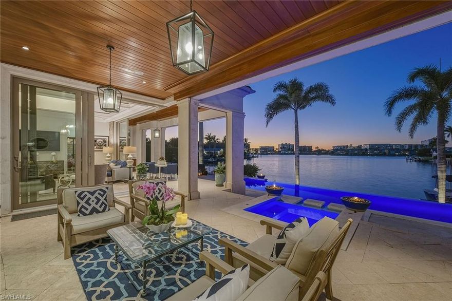 From the moment the front door opens, the bay becomes the focal point. Built by renowned BCB Homes, this custom estate was conceived to showcase the waterfront at every turn while delivering a level of detail and finish expected by the discerning buyer. The home unfolds through a thoughtful balance of formal and casual spaces, each designed to serve a purpose while maintaining visual continuity with the bay. Formal living and dining rooms create an elegant framework for entertaining, while everyday living naturally gravitates toward the family room, where expansive glass captures panoramic water views throughout the day. At center of the residence, the kitchen functions as a gathering space and a showpiece. Dual islands provide scale and flow, while marble countertops and professional appliances support serious cooking and entertaining. The 60-inch Wolf gas French plate range is not simply a feature but a statement, underscoring the home’s commitment to performance and design. Nearby, a dedicated bar and climate-controlled wine room anchor the home as a setting for evenings that linger. Inspired by coastal Europe, the home’s outdoor areas are anchored by an infinity-edge pool and spa that visually merge with the bay beyond. Covered and open-air spaces are layered to accommodate every part of the day, from shaded afternoons on the lanai to evenings around the summer kitchen and open sitting areas. The custom 90-foot dock extends the home’s lifestyle onto the water. Designed to blend naturally with its surroundings, it is equipped with a 16,000-pound lift and floating dock platform, ready to support aquatic adventures. The first-floor primary suite occupies a dedicated wing of the home with a bedroom positioned directly on the bay, offering sweeping water views upon waking and retiring. Dual walk-in closets and a marble-clad bath evoke the best European spas, while a secluded sitting room or office provides a quiet place to work or reflect. The first floor also features a beautifully finished billiards room or fifth bedroom, complete with its bath, allowing the home to adapt effortlessly. The second floor, with its dedicated elevator, features three beautifully appointed guest suites, each with a private en-suite bath. A central social room with a morning bar creates a natural gathering point for guests, reinforcing the home’s sense of ease and hospitality. The second-floor balcony offers expansive bay views, while the rooftop terrace provides an even more commanding perspective. With a dedicated fireplace and open vistas across the water, this space becomes a destination for sunsets, evening conversations and quiet moments above it all. This Moorings bayfront residence is not simply a home but a setting for a life shaped by water, light and thoughtful design.