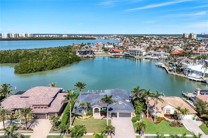 Enjoy a captivating bay view with quick direct access to the Gulf of Mexico from your recently built oversized private dock with a 16,000-pound boat lift and a 7,500-pound platform lift. This extraordinary four-bedroom plus office and den home is a gathering place for friends and family, offering soaring ceilings and abundant space in the open floor plan with formal living and dining areas, a kitchen, breakfast nook and family room. Relax poolside under the screened lanai with a built-in outdoor gas fireplace and spa. A spacious primary suite is on the first floor along with two guest rooms on the other side of the home. Upstairs two more guest rooms complete with a kitchenette and wine cooler flow out to a cozy balcony overlooking the tranquil bay. Pocketing impact glass sliders, impact windows, a security system, storm shutters and a massive three-car garage with tall ceilings that can accommodate car lifts are also of note. This tastefully updated custom-built home offers luxurious comfort. The chef’s kitchen features a Wolf gas cooktop and Wolf wall ovens complete with a 48-inch Sub-Zero built-in refrigerator and KitchenAid dishwasher. The pool and spa are controlled by an Aqualink system and electric heat. An additional gas line was run for the barbecue grill served by a 200-gallon propane tank. A brand new flat tile roof and new gutters were just installed in 2025 for peace of mind and lower insurance costs. Seller has a transferable NFIP flood insurance policy.