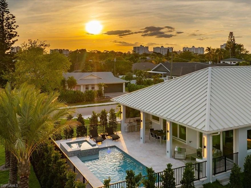 Elevated above the surrounding streetscape on an oversized corner homesite, this calm and thoughtfully executed coastal contemporary residence delivers a rare sense of openness, privacy, and modern livability within the heart of Naples Park.

Offering 3 bedrooms and 3.5 baths, the home was designed around seamless indoor-outdoor living and elevated modern comfort. The placement of the home within the oversized corner homesite creates an unusually open and private setting, with the pool terrace and covered living areas elevated prominently above the surrounding streetscape. Nearly 1,000 square feet of covered and open-air living space surrounds the pool and spa, including expansive entertaining areas, a built-in kitchen and grill station, and wide western sunset exposure.

Inside, the finishes are refined yet warm, with large-format porcelain flooring featuring subtle veining, soaring ceilings, expansive impact glass openings, and clean contemporary lines throughout. The chef’s kitchen is anchored by a professional-grade Thermador gas range, oversized paneled refrigeration with integrated interior camera technology, extensive cabinetry, and a one-touch Miele coffee system.

All three bedrooms feature private ensuite baths and built-out closet storage. The primary suite offers direct poolside access along with a spa-inspired bath featuring dual vanities, spacious walk-in shower, and carefully selected finishes throughout.

Fully completed and move-in-ready, the home was executed to an exceptional construction standard with a standing seam metal roof, fully insulated roof deck creating conditioned attic space, commercial-grade Speed Queen laundry, buried 1,000-gallon propane tank, and a 24kW whole-house Generac generator.

Additional highlights include an epoxy-coated garage with additional storage capacity, professionally designed landscaping, extensive paver hardscaping, and exceptional proximity to Vanderbilt Beach, Mercato, Waterside Shops, and Naples’ premier dining and shopping destinations.