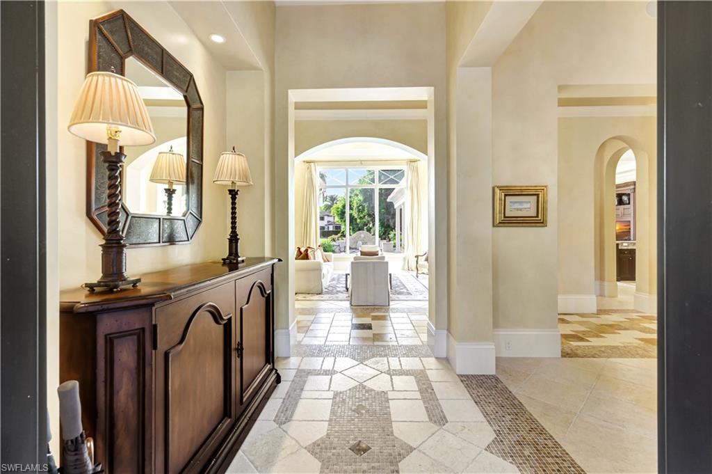 Elegant entryway of luxury home in Miramonte, featuring a decorative console table, ornate mirror, and soft lighting, leading to spacious living area with large windows and outdoor views.