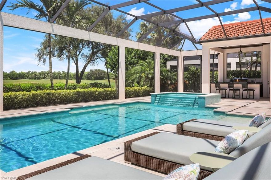 In prestigious Fiddler’s Creek, this exceptional luxury residence offers expansive golf course views, professional landscaping, and delightful outdoor lighting. The charming French door entry opens to inviting 14-foot ceilings, a distinctive foyer, and stunning designer flooring. The exceptional living area opens through 10-foot impact glass doors to the breathtaking pool and summer kitchen beyond. Sun-shelf, bubblers and a delightful spa with sparkling multi-colored tile invite you to spend lots of time in the pool. The wood accent ceiling has a warm and inviting effect on the overall impression of the outdoor area. Inside, the open-concept great room embraces formal dining with seamless access to the expanded lanai. The gourmet-style dining and kitchen area features an oversized island with stunning white quartz and KitchenAid appliances. The custom cabinetry with additional height and glass front doors is exceptional. Pullout shelving, and a custom-designed range hood complete the desirability of soft tropical elegance. Plantation shutters, custom lighting, and ceiling fans exist throughout the home. A sitting area in the primary main suite contributes to the home’s refined style. An exceptionally large walk-in closet is always a good idea and this home has it. The gorgeous main bath is unique and beautifully appointed. Additional features include a three-car garage, extended driveway, and enhanced exterior elevation. The three additional bedrooms are all en suite and continue the color and style of the overall decor. Each with oversized closets. A delightful powder room and niche just off the entrance hallway gives character and appeal to this lovely home. A large laundry room and superior, side-load, three-car garage complete the picture. Residents enjoy award-winning amenities of Fiddler’s Creek, including many new pickleball and tennis courts, a newly remodeled lagoon-style pool, spa and fitness center, with the benefit of gracious formal dining as well as outdoor grill and other dining venues. Recreation opportunities are numerous as well as the option of golf, beach and boating memberships. Minutes from the amenities of Old Naples and Marco Island, this gorgeous home is a delight.