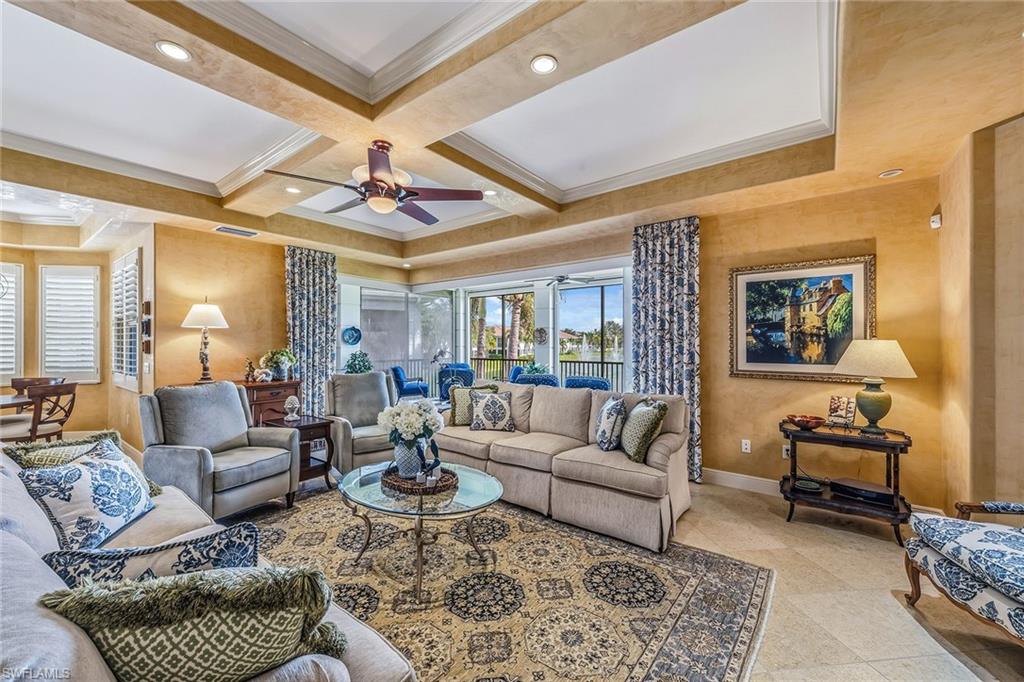 Luxurious living room in a three-bedroom, four-bath condominium at Avellino Isles, featuring elegant furnishings, decorative pillows, and a scenic view through large windows, emphasizing a relaxing lifestyle.