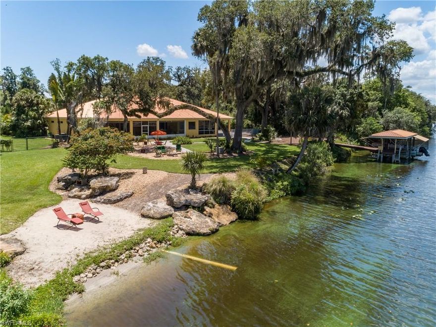 Schedule your private showing of this amazing 3.5 acre riverfront paradise today! The main house boasts a large master bedroom with a gorgeous view of the Caloosahatchee River, a large master bathroom with two walk-in closets and a private screened lanai. The recent renovation of the kitchen (2019), included new appliances and the addition of a bar, allowing views of the river and game room/living room. The main lanai provides several sitting areas and easy access to your own private boat dock, a riverfront beach and 200 ' +/- on the river. The attached, oversized two car garage is huge and features abundant built-in storage. The well water is pumped through a  whole house reverse osmosis system which was replaced/upgraded in 2019. A submersible pump in the river (replaced 2021) runs the irrigation system.  
The quaint guest house features a private driveway and lanai, full kitchen and bath, and a loft that doubles as a bedroom.
A 24 ft. x 18 ft. pole barn, enclosed 12 ft.x 12 ft. shed, open under roof shed and an enclosed 16 ft. x 8 ft. pump house provide additional storage for toys, motorhomes, etc. The grounds are meticulously landscaped, making this a nature lover's paradise.