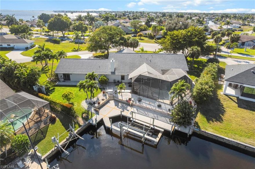 Experience one of Cape Coral’s rarest offerings—6 1/2 car garage and direct no bridges sailboat gulf access on a sweeping intersecting canal. This pool home is situated on a ½-acre lot with just one turn to the river delivering the kind of waterfront lifestyle we move to Florida for. The spacious island kitchen features granite countertops, abundant cabinetry, and a breakfast nook open to the cozy family room with fireplace. The first-floor primary suite is its own retreat, complete with a private atrium, a spa tub, and overlooks the pool and canal. The second story offers a versatile office or den with a half bath—an ideal getaway space for work, hobbies, or overflow guests. This property is loaded with major improvements: a 2017 metal roof, whole-house generator with a 500-gallon propane tank, whole-house water filtration, roll-down and manual shutters throughout. Outside, the boating experience is exceptional with a composite dock, captain’s walk, and boat lift. A screened-in pool area and additional paver patio with sunshade create multiple zones for outdoor living while capturing the tranquil water views. With its oversized lot, sailboat access, and unmatched garage space, this home brings together comfort, convenience, and the best of waterfront living in a way that rarely comes to market.