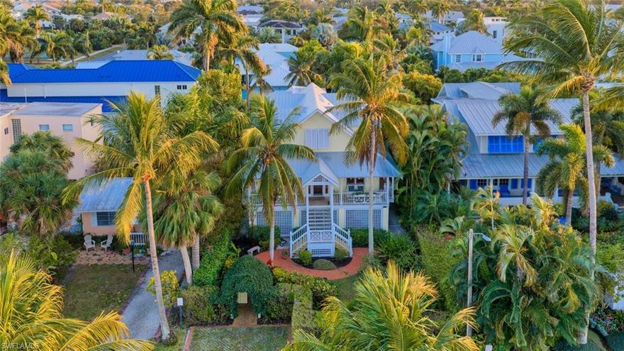 Timeless Old Florida charm defines this ideally located residence, positioned between the 3rd Street South and 5th Avenue South entertainment districts and just three blocks from iconic 5th Avenue South. This enchanting four bedroom plus den residence offers 2,909 square feet of living space, three full and one half baths, and a welcoming wraparound porch that sets the tone for relaxed coastal living. Tucked just off Cambier Park, the property features a thoughtfully connected two-story guest house with living space on the lower level and a private bedroom above—ideal as a primary suite, guest quarters, extended-family accommodation, or a private office retreat. The upper level of the main home showcases two bedrooms and a loft beneath a vintage tongue-and-groove wood-plank ceiling, with both bedrooms opening to private balconies that capture gentle coastal breezes. The main floor includes the kitchen and great room, along with a fourth bedroom or den with en-suite bath. Classic Old Florida storm shutters add both character and function. The generous backyard offers ample room for a pool and outdoor entertaining, while a rear-entry two-car garage off the paved alley provides convenience and additional parking. Private front and rear yards are framed by mature hedging, with a charming archway entry, quaint wooden gate, and parking for two vehicles off 8th Avenue South, plus additional parking in the rear. A 2019 metal roof adds peace of mind. Located directly across from Cambier Park, offering a competitive tennis program, shuffleboard courts and bocce, covered pavilion, band shell, and expansive green space. Close to everything, welcoming, and rich in character—this is a rare opportunity to own a true downtown Old Florida cottage.