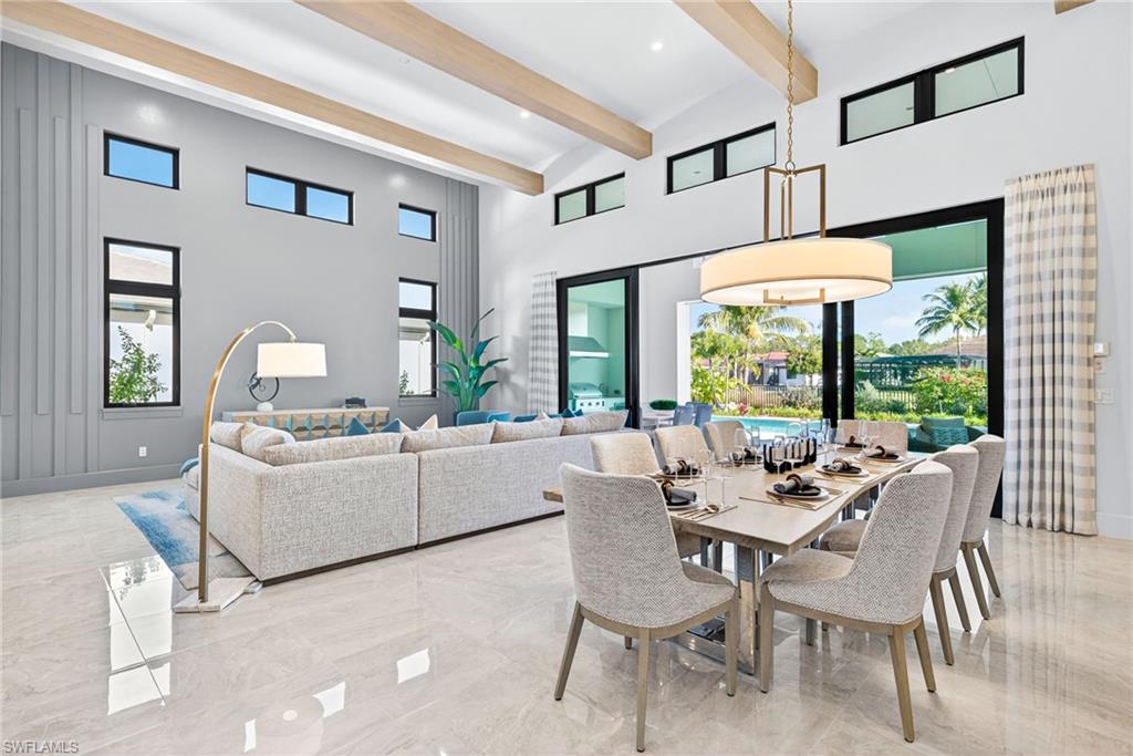 Modern living room and dining area with elegant furnishings, large windows showcasing lake views, and a spacious layout ideal for entertaining, featuring a stylish dining table set for guests.