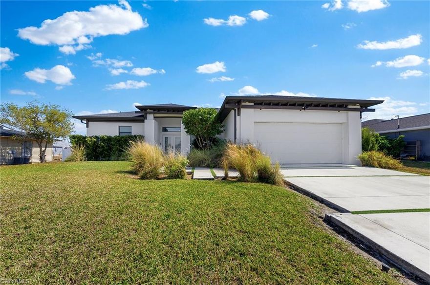 Modern luxury meets striking architectural design at **1823 NE 19th Ave** in Cape Coral. **Peace of mind is built-in, as this residence is located in Flood Zone X, meaning no flood insurance is required.** From the moment you arrive, the home commands attention with custom architectural outriggers, a contemporary driveway and walkway, and beautifully curated modern landscaping that sets the tone for what awaits inside.

At the heart of the home is a show-stopping designer kitchen featuring a dramatic statement island wrapped in book-matched **Calcutta Borghini**—an absolute centerpiece perfect for entertaining and gathering. The designer and builder took pride in every decision and it shows at every turn! The open living space is elevated by soaring coffered ceilings, bold contemporary fixtures, and a stunning floor-to-ceiling pivoting glass door that reveals a sophisticated home office.

The private owner’s suite offers a luxurious retreat with dual walk-in closets and a spa-inspired bathroom designed for ultimate comfort and relaxation. Two additional bedrooms provide space for family or guests, while thoughtful details such as a walk-in kitchen pantry and a stylish indoor laundry room reflect the same level of craftsmanship and attention to detail found throughout the home.

When you step outside into your expansive screened lanai, you will enjoy the large fully fenced yard and kids' play area. This residence is a perfect blend of modern elegance, architectural character, and everyday functionality—delivering a truly elevated living experience in one of Cape Coral’s growing areas.