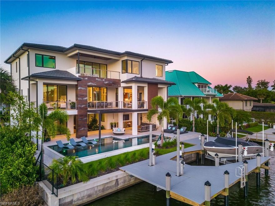 Experience the allure of Naples sunsets from this one-of-a-kind custom home, designed to immerse you in the ultimate beach and boating lifestyle. Situated in the coveted neighborhood of Vanderbilt beach, this southern facing property overlooks the bay across from the new Ritz Carlton Residences and is a short stroll away from Naples' renowned beaches.From the meticulously crafted floor plan to the high end finishes and unmatched structural integrity, this home exudes sophistication. As you enter, you're welcomed by a bespoke Walnut staircase with glass railings, leading your gaze to the resort-style pool, boat dock with two lifts, and the tranquil waterway.The main living area embodies an open-concept indoor/outdoor design, anchored by a custom Walnut chef's kitchen, featuring both Miele and Signature appliances and a butlers pantry. The adjoining great room showcases a unique accent wall, while the dining area boasts a glass-enclosed, illuminated wine wall adorned with custom pecky cypress accents. Extend your living space outdoors with a plush outdoor living room, kitchen, fireplace, and dining area--all overlooking the bay. The primary suite, also on the main level, offers breathtaking sunset views and an opulent primary bathroom highlighted by a backlit crystallo accent wall, rose gold fixtures, and custom walnut cabinetry. Complementing the main level, the home features Walnut flooring throughout, an additional living or game room, a fitness gym, a 4 car tandem garage, a Private elevator, and ample storage space. With too many upscale features to enumerate, this home is a must see. Conveniently located minutes away from shopping, dining, entertainment, resorts, and beaches, it captures the essence of luxurious living in vibrant South Florida.