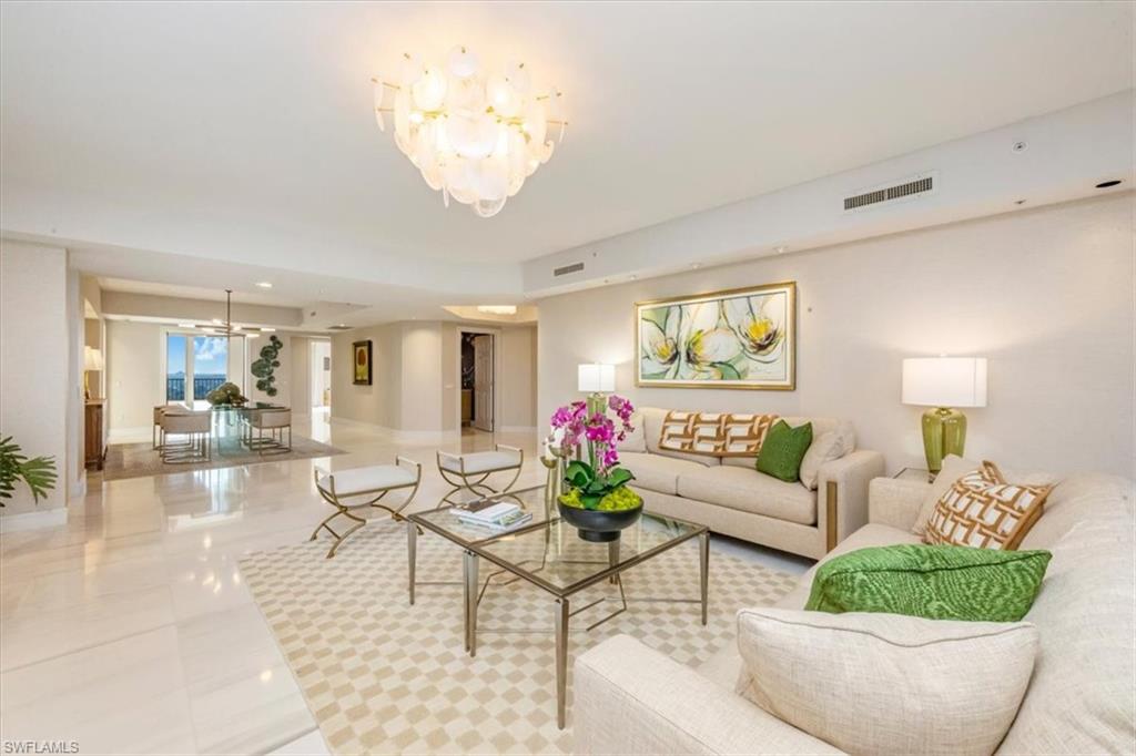 Designer-renovated living room in luxury Montenero condominium, featuring elegant furnishings, large windows with Gulf views, and a spacious open floor plan.