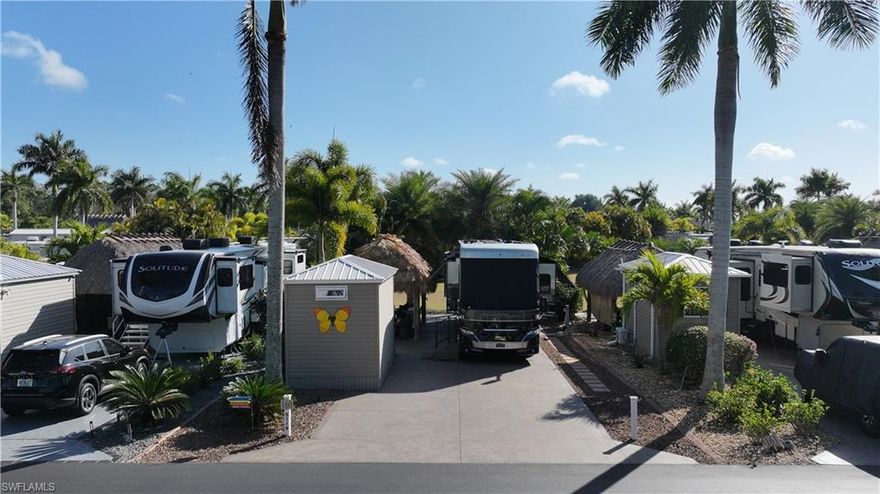 Experience exceptional outdoor living at Site 160, a beautifully landscaped RV lot located in one of Fort Myers’ most desirable luxury RV resorts. This spacious property offers privacy, mature tropical landscaping, and an impressive entertaining setup.
The lot is surrounded by established Sylvester, Calusa, and Royal palms along with additional tropical foliage, creating a lush and private setting. An oversized tiki hut — recently rethatched and equipped with electric — serves as the focal point of the property, providing a generous shaded space ideal for relaxing or entertaining.
The site backs to a large common area, offering added privacy with no immediate rear neighbors and open green space views. The painted concrete pad is in excellent condition and complemented by extended pavers, expanding the usable outdoor living area.
An accessory building on the property provides a blank canvas for customization, allowing the next owner to design and finish the space to suit their needs.
With strong value, mature landscaping, and outstanding outdoor living features, Site 160 presents an excellent opportunity to enjoy the Florida RV lifestyle in a well-maintained, amenity-rich community.