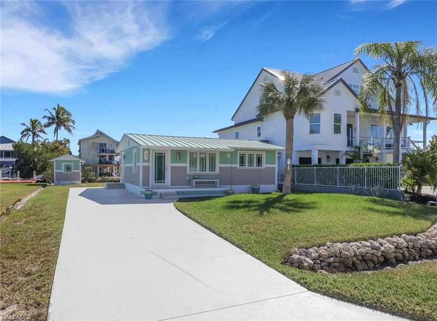 Positioned just one lot from the end of the canal, the Sand Dollar Cottage enjoys breathtaking views toward the Cocohatchee River while offering direct Gulf access within minutes. Rebuilt to reflect the original 1960s Mackle Brothers South Florida coastal philosophy, this residence blends architectural heritage with artful craftsmanship. Raised porches crafted from hand-laid sea glass, fossil stone, and mosaic elements create a striking welcome, complemented by 8-inch half-round architectural gutters and period-correct rain chains. A standing-seam roof of high-gauge metal, and PGT impact resistant windows and doors provide both style and peace of mind.
Existing pilings allow for dock installation in the original footprint, and a matching boathouse structure offers flexibility for storage, entertaining, or a waterfront bar concept. 

Inside, the coastal fishing cabin ambiance is elevated through exposed wrapped beams, horizontal whitewashed ceiling planks, and layered up lighting designed to emulate vintage gaslight warmth. Level 5 Cambria quartz countertops wrap the kitchen, complemented by custom cubbies with barrister doors for wine and specialty drinkware. Appliances include a three-burner induction cooktop, beverage refrigerator, convection oven with air fry and broil functions, and thoughtfully integrated workstation pass-through. Two fireplaces with concrete hearths are approved for insert conversion, while vaulted rod holders and curated mid-century furnishings enhance the thematic cohesion. The primary suite boasts a 12-foot vaulted ceiling, and the bath showcases dimensional tilework with a glass-wall shower and built-in cabinetry. Wall-mounted pivoting fans add both function and aesthetic detail. With no community rental restrictions and exceptional character rarely found on Naples waterfront, this cottage presents an outstanding opportunity as a personal retreat, guest overflow residence, or high-performing short-term rental investment.