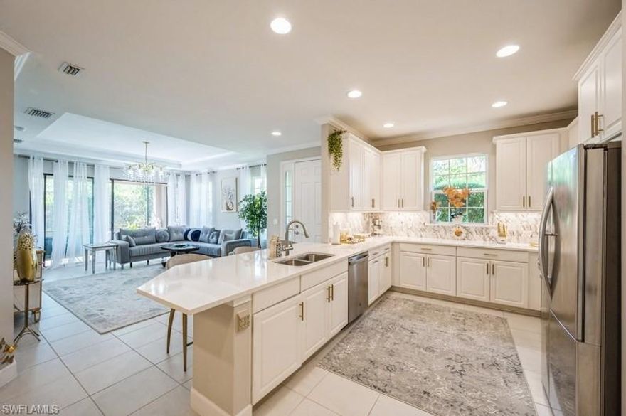 Experience elevated coastal living in this east-facing 2-bedroom + den, 2-bath corner villa in Esplanade at Hacienda Lakes. Designed for both comfort and style, this light-filled, move-in-ready home offers exceptional privacy and a seamless, open-concept layout ideal for everyday living and entertaining.

The flexible den with double doors provides the perfect space for a private office or can easily convert into a third bedroom. At the heart of the home, the designer kitchen features quartz countertops, a custom backsplash, modern hardware, newer appliances, a spacious pantry, and an inviting breakfast bar.

The primary suite serves as a peaceful retreat, highlighted by a custom walk-in closet and a spa-like bath with dual vanities and a walk-in shower. Luxury vinyl plank flooring runs throughout the entire residence—including closets—offering a sleek, cohesive look with no carpet anywhere.

Thoughtful upgrades continue with crown molding, statement lighting fixtures, a guest bath with frameless glass shower door, window treatments, and a well-appointed laundry room with utility sink. A 2-car garage adds both convenience and functionality.

Enjoy tranquil mornings and shaded afternoons from your private screened lanai, complete with a ceiling fan and serene outdoor setting.

Residents of Esplanade at Hacienda Lakes enjoy a true resort lifestyle, with access to a beautifully appointed clubhouse, fitness center, pickleball, tennis, bocce courts, and a resort-style pool with spa and cabanas.

Ideally located in Naples, just minutes from premier shopping, dining, Physicians Regional Hospital, downtown 5th Avenue, and the pristine beaches of Marco Island.

A perfect blend of privacy, modern upgrades, and prime location—this home defines effortless Southwest Florida living. No flood insurance is required.