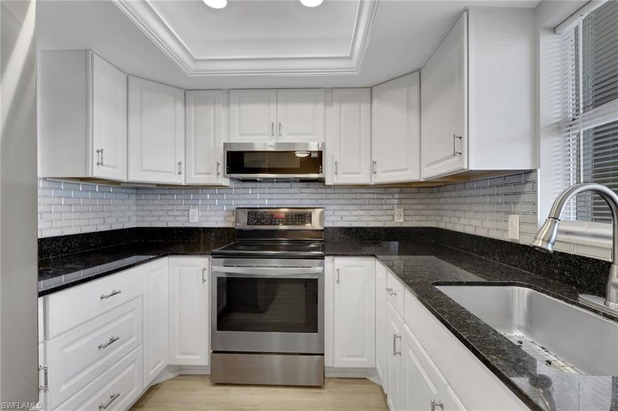 This well appointed two bed/two bath condo has been tastefully updated and is move-in ready. There is newly installed flooring in the living and dining areas, as well as both bathrooms. The kitchen updates include white cabinetry, granite counters, stunning backsplash, stainless steel appliances, and tray ceiling with recessed lighting and crown molding. The bedroom closets are spacious with great storage options. Additional updates include Interior doors/hardware, base trim, lighting fixtures. The rear screened lanai has custom tile and newer washer and dryer. The peaceful view from the lanai includes the lake, beautiful, landscaped area and the golf course. It is a relaxing space to start or end your day, while enjoying the wildlife and the shore birds. There is designated parking in the covered carport next to the building. Country Club Manor is a friendly 55+ community with a large pool, clubhouse and barbeque area just steps from the condo. In addition, the location is very close to the public golf club.  The beaches of Naples and the vibrant downtown are less than 5 miles away!